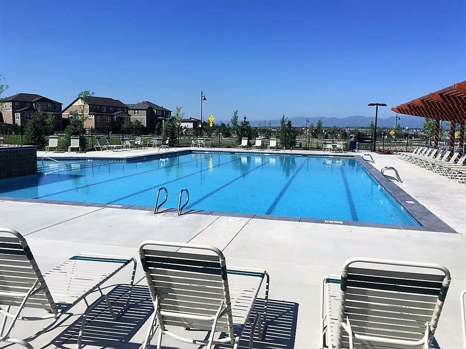 A large swimming pool with chairs around it on a sunny day.
