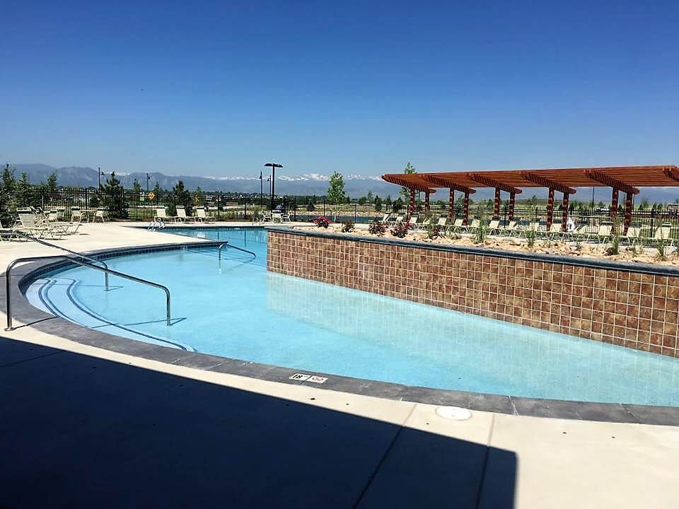 A large swimming pool with a pergola and mountains in the background.
