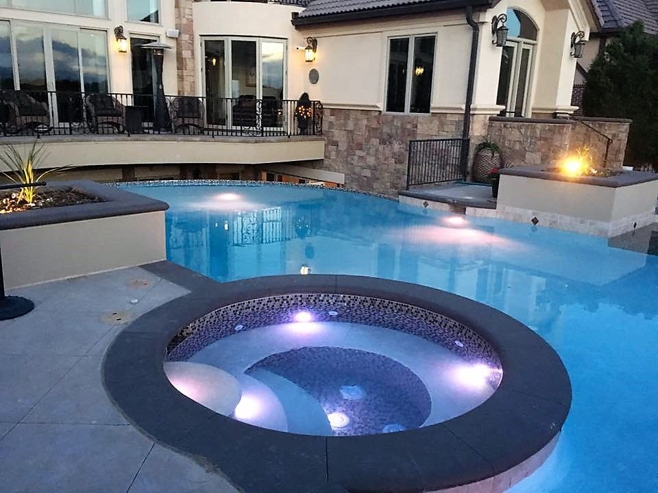 A large swimming pool with a hot tub in the middle.