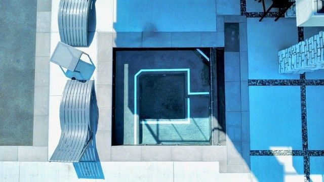 Overhead view of a modern outdoor space with a pool, seating, and white and blue tones.