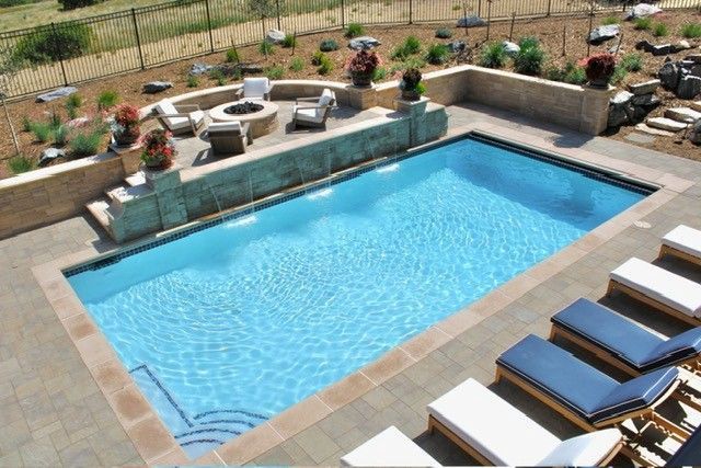Rectangular swimming pool with water features, patio, and lounge chairs.