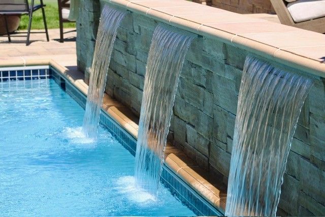 Pool with water cascading from stone wall.