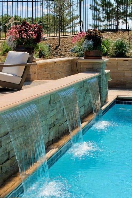 Swimming pool with cascading waterfalls and lounge chair.