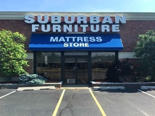 Suburban Furniture Mattress Store storefront with blue awning and sign on brick building.