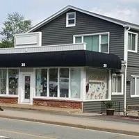 A small business building with a black awning and multiple windows, located on a street.