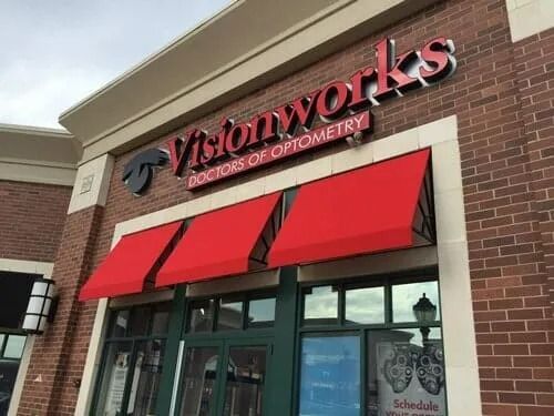 Visionworks storefront with red awnings and signage on a brick building.