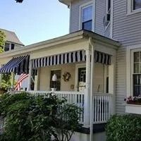 House with porch, blue and white striped awnings, and American flag.