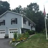 Blue house with awnings and American flag in front.