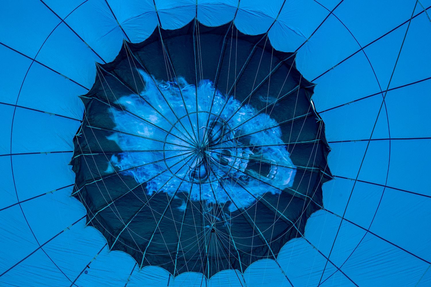 Inside blue hot air balloon, looking up; flames in the center.