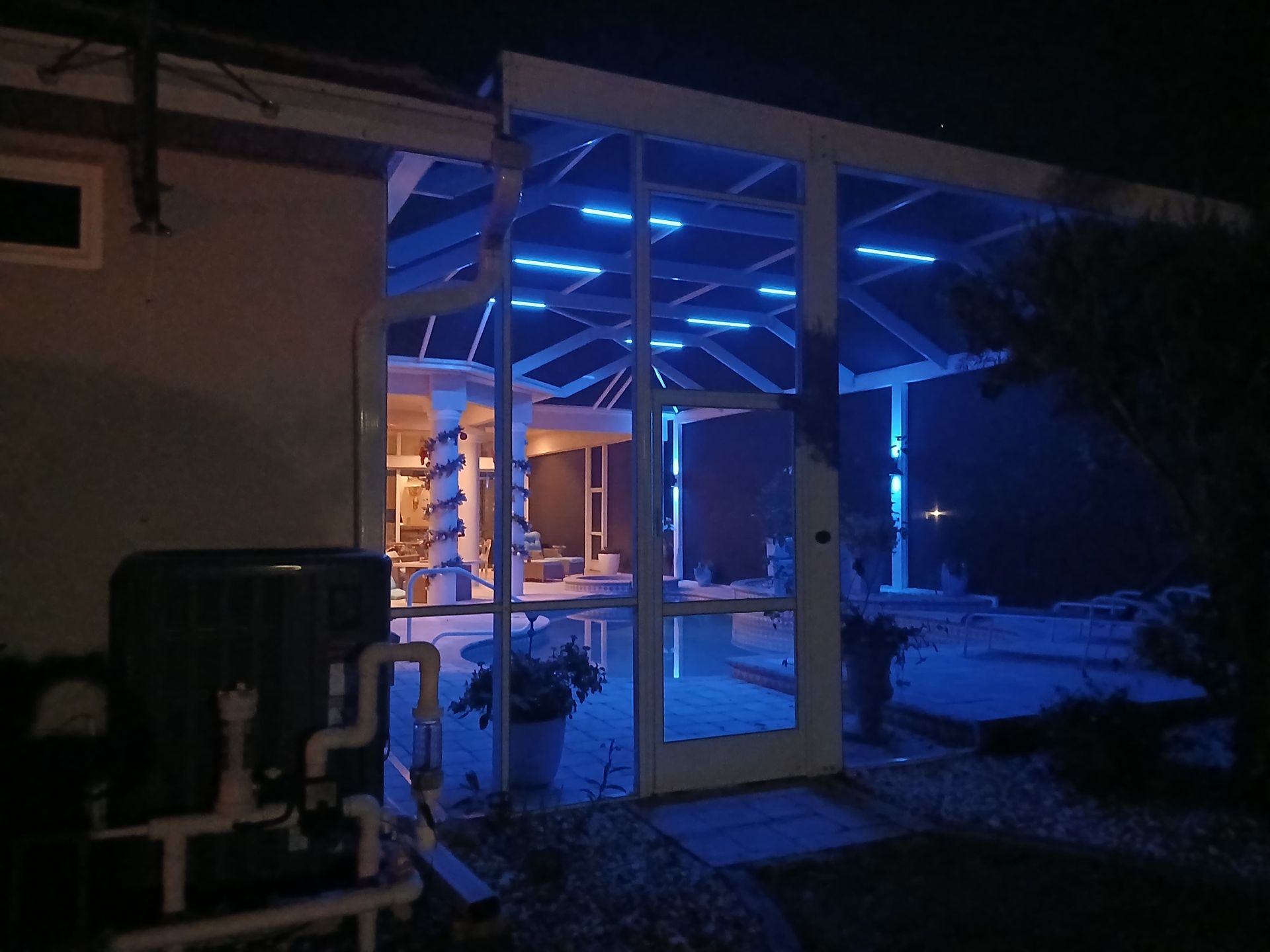 Blue LED lights illuminate a screened-in patio at night. Interior is visible, showing a lit area.