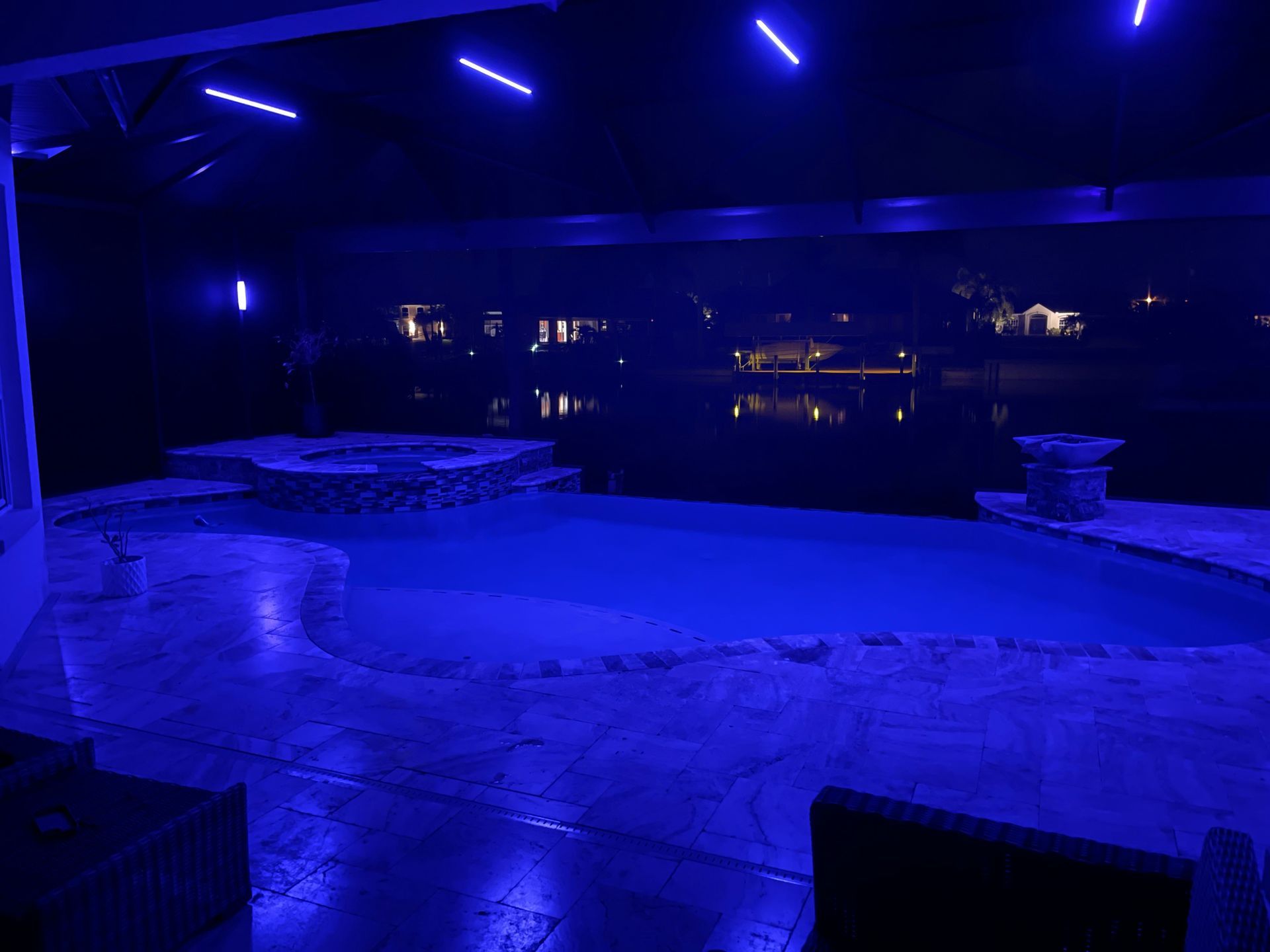 Blue-lit outdoor patio overlooking dark water at night