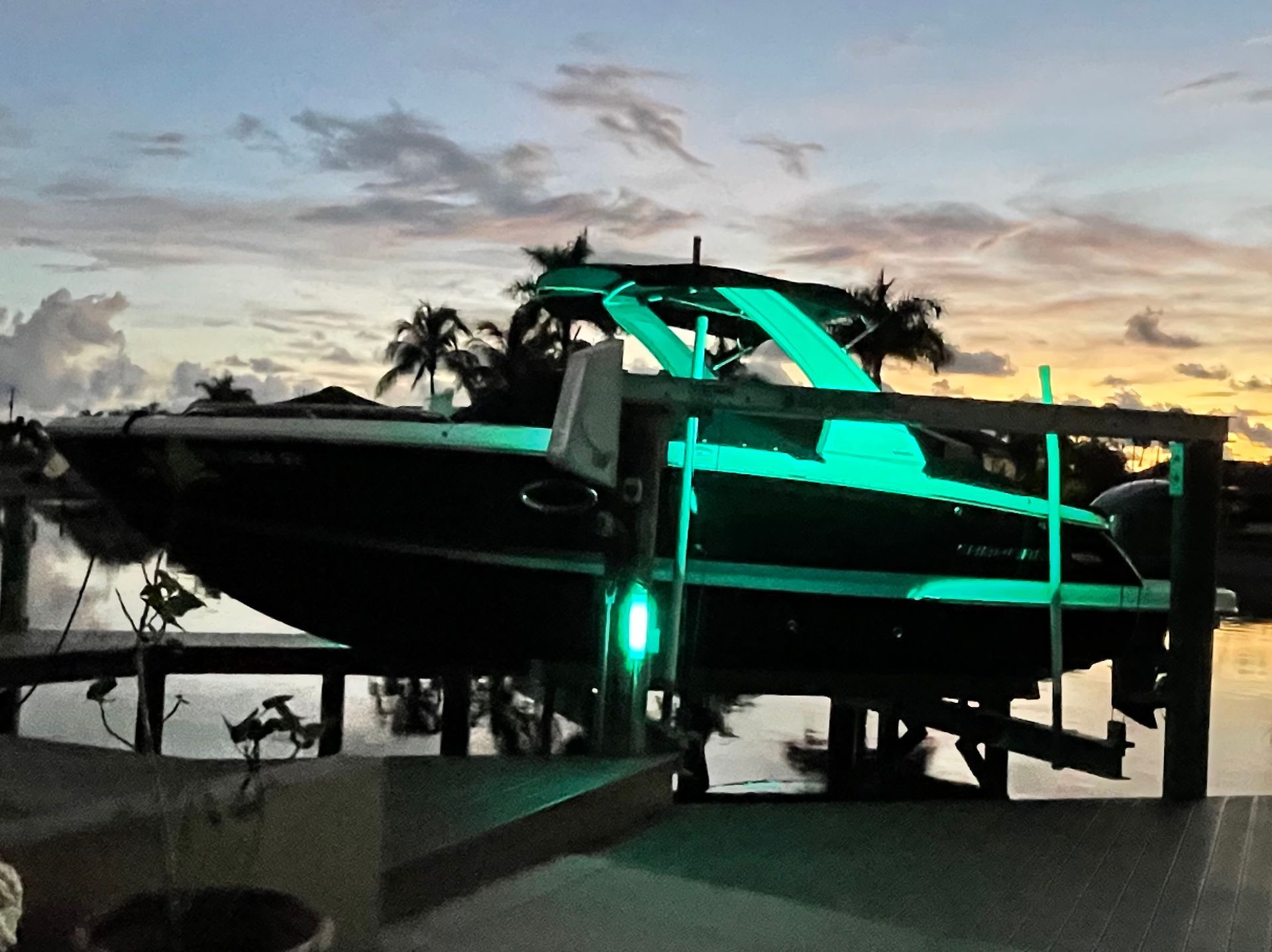 Futuristic black vehicle with glowing green lights on a platform at dusk