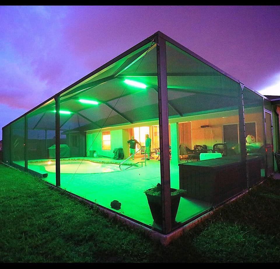 Green-lit pool enclosure at dusk, with house interior visible.