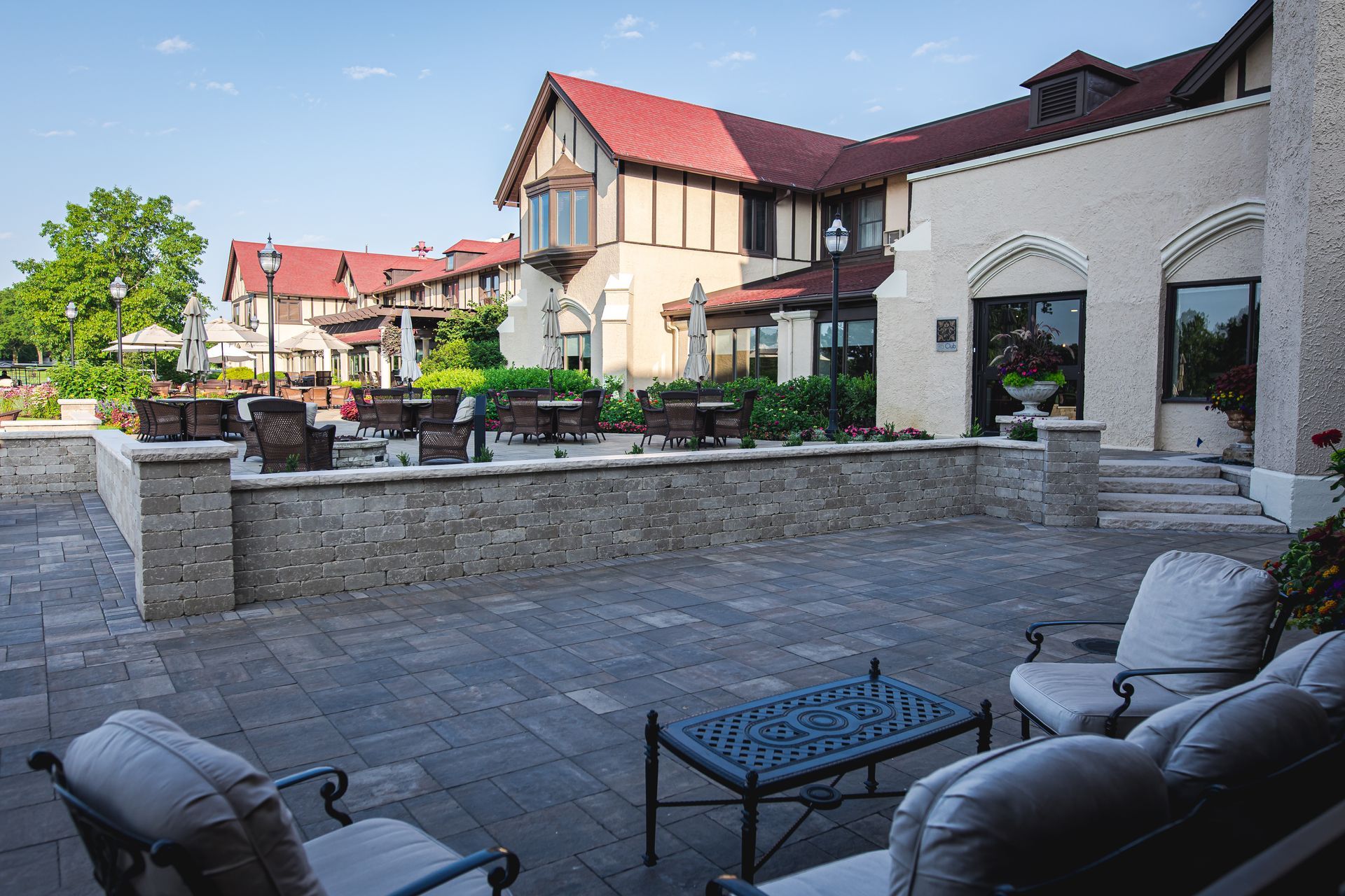A patio with chairs and a table in front of a large building.