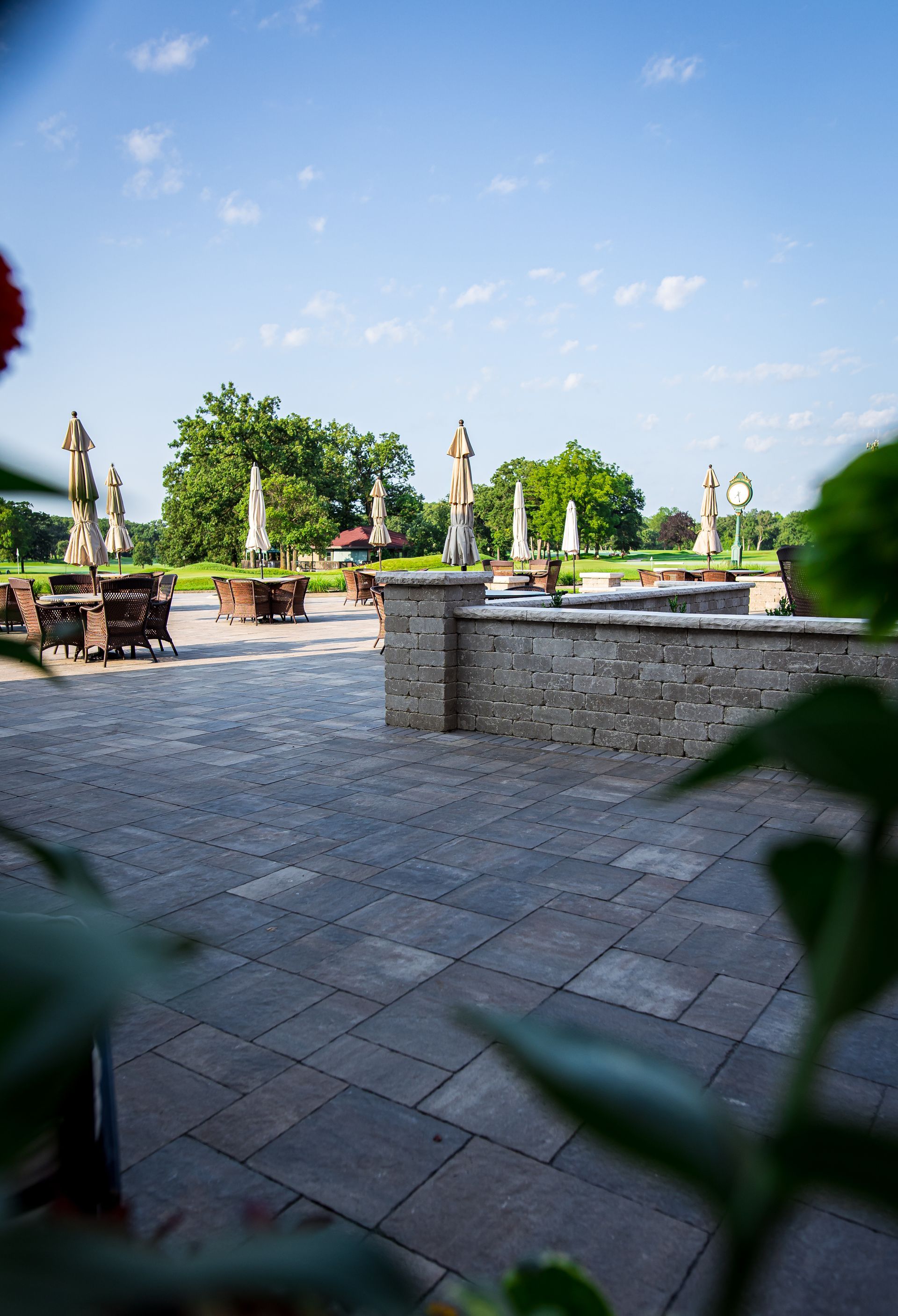 A patio with tables and chairs and umbrellas on a sunny day.