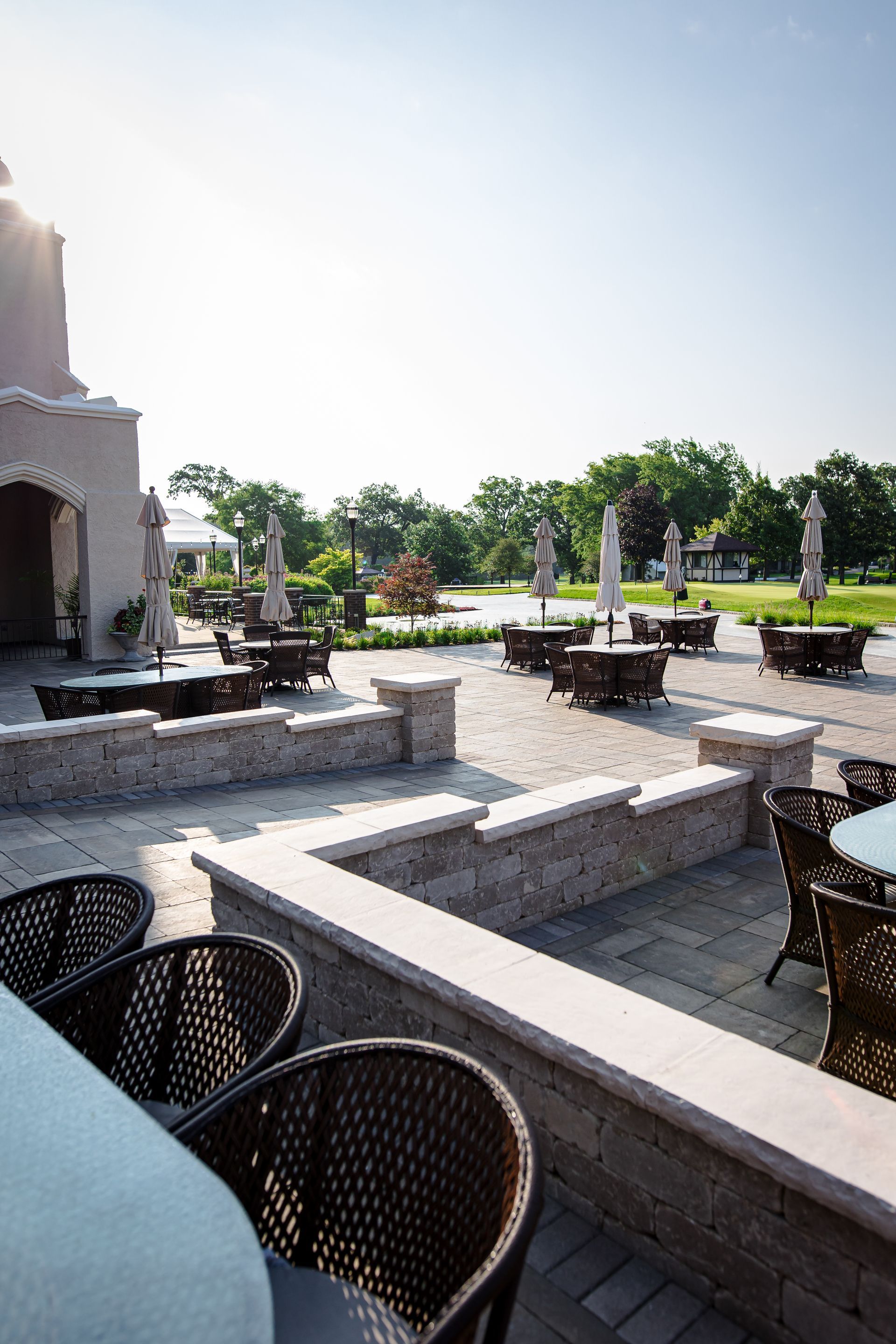 A patio with tables and chairs and umbrellas on a sunny day.