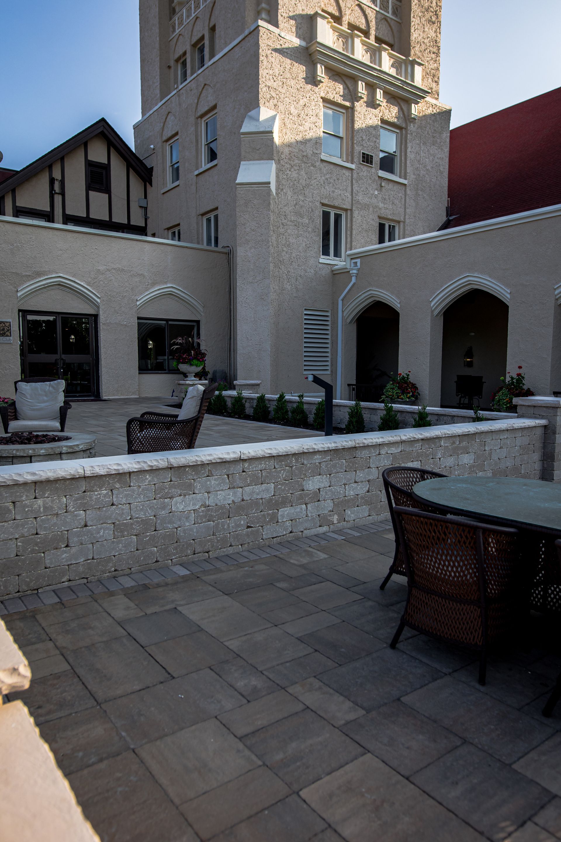 A patio with a table and chairs in front of a large building.