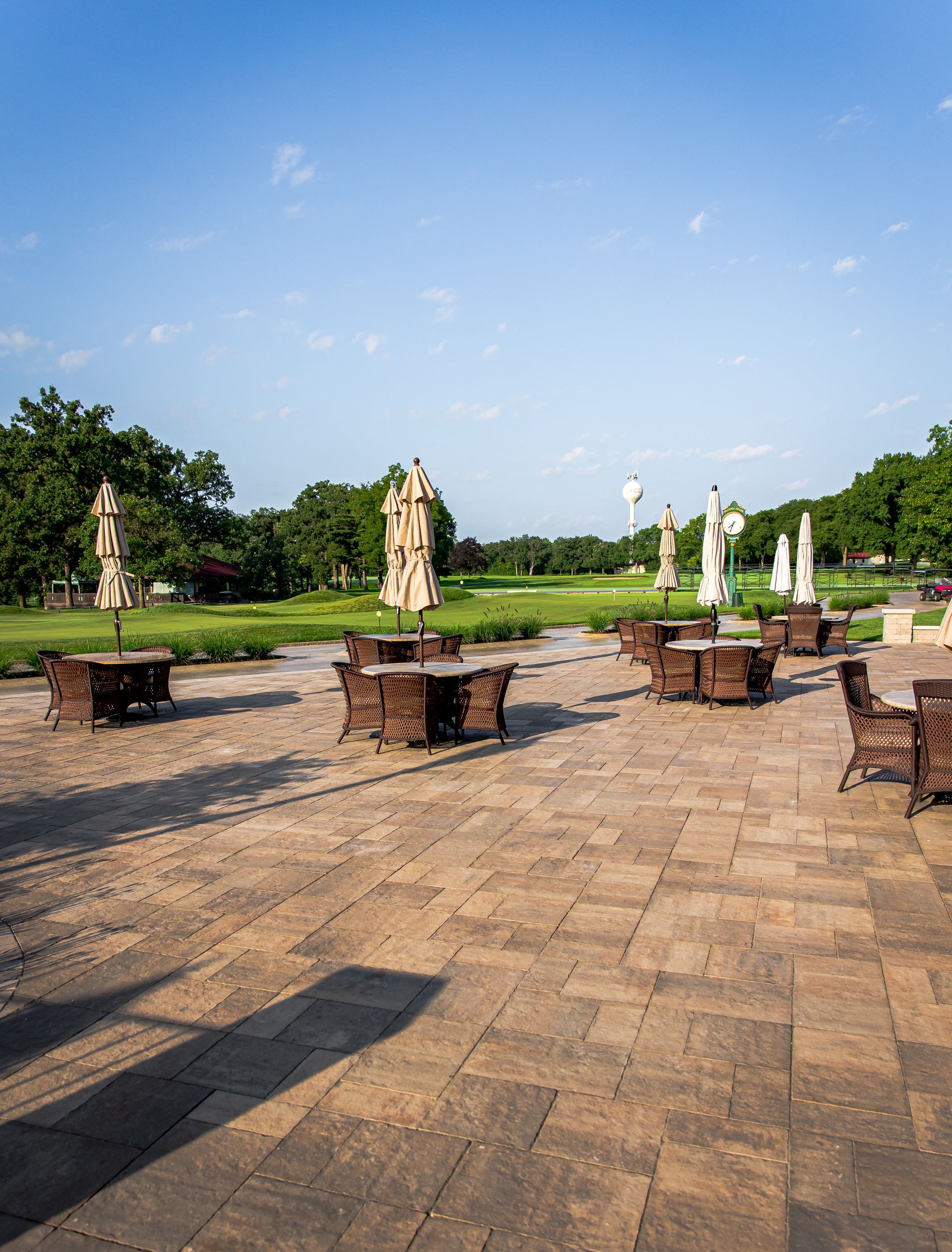 A patio with tables and chairs and umbrellas in a park.