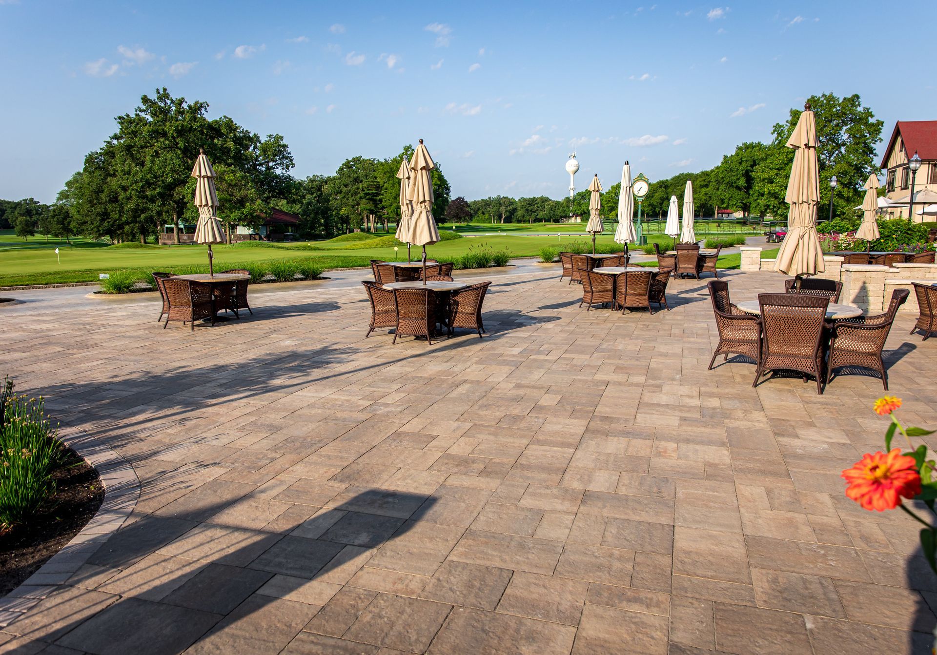 A patio with tables and chairs and umbrellas on a sunny day.