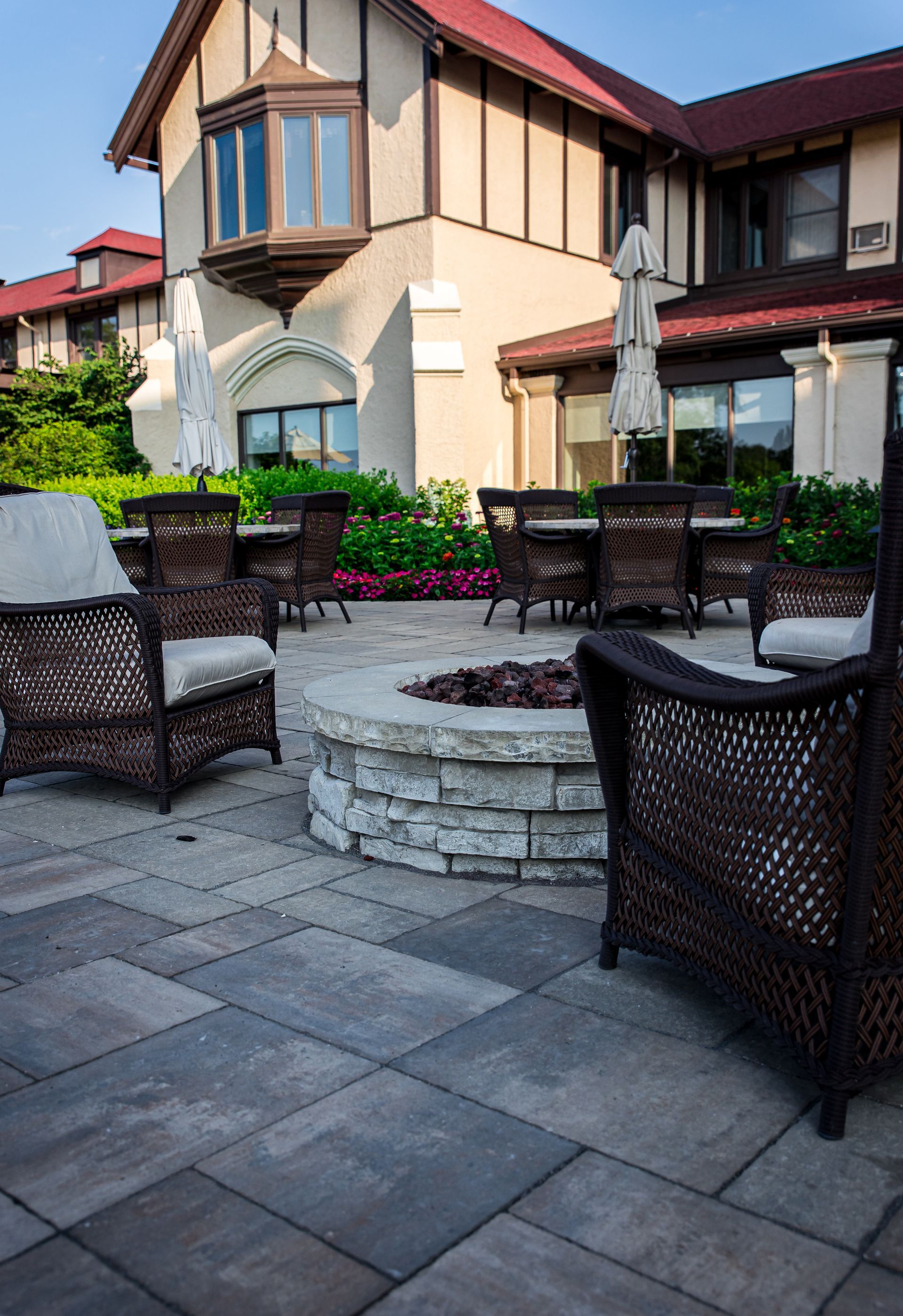 A patio with chairs and a fire pit in front of a house.