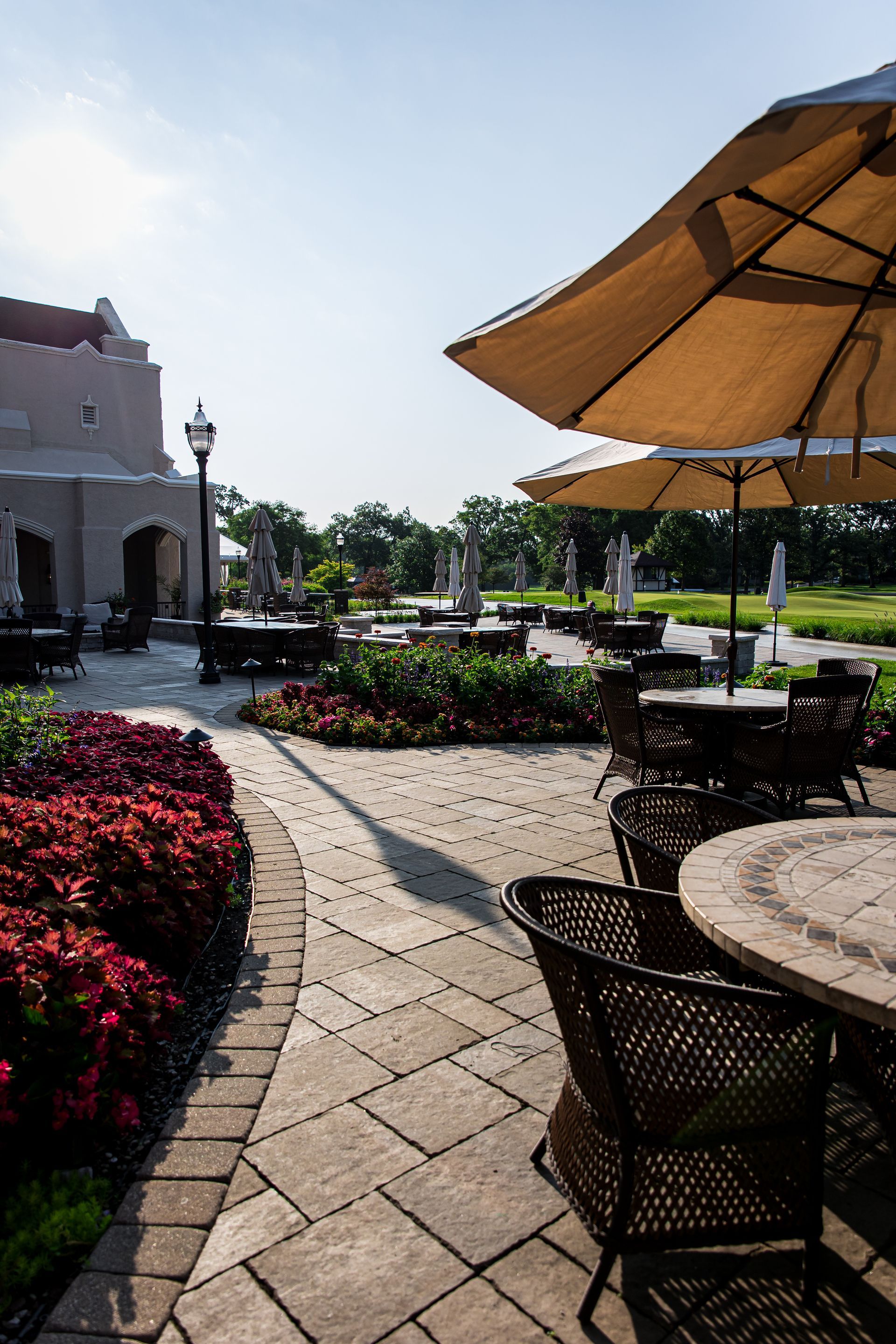 A patio with tables and chairs and umbrellas on a sunny day.