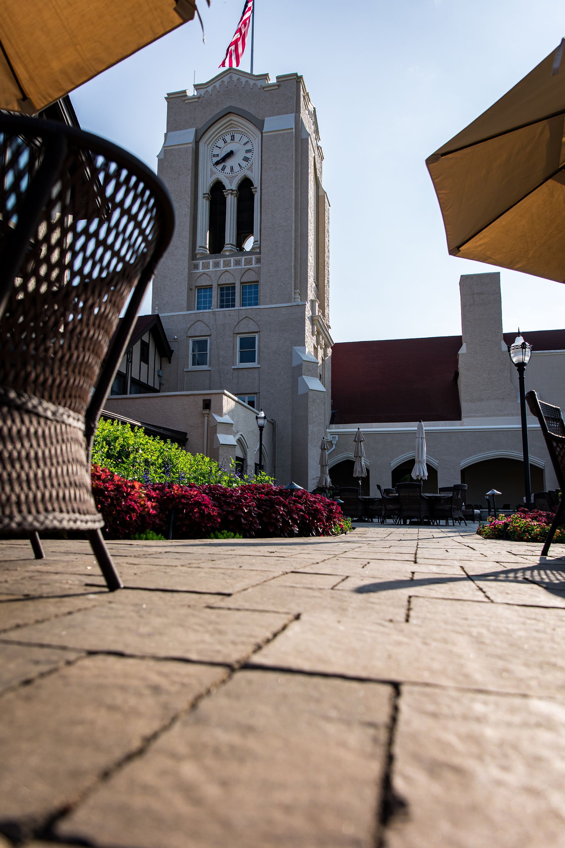 A large building with a clock tower is surrounded by chairs and umbrellas.