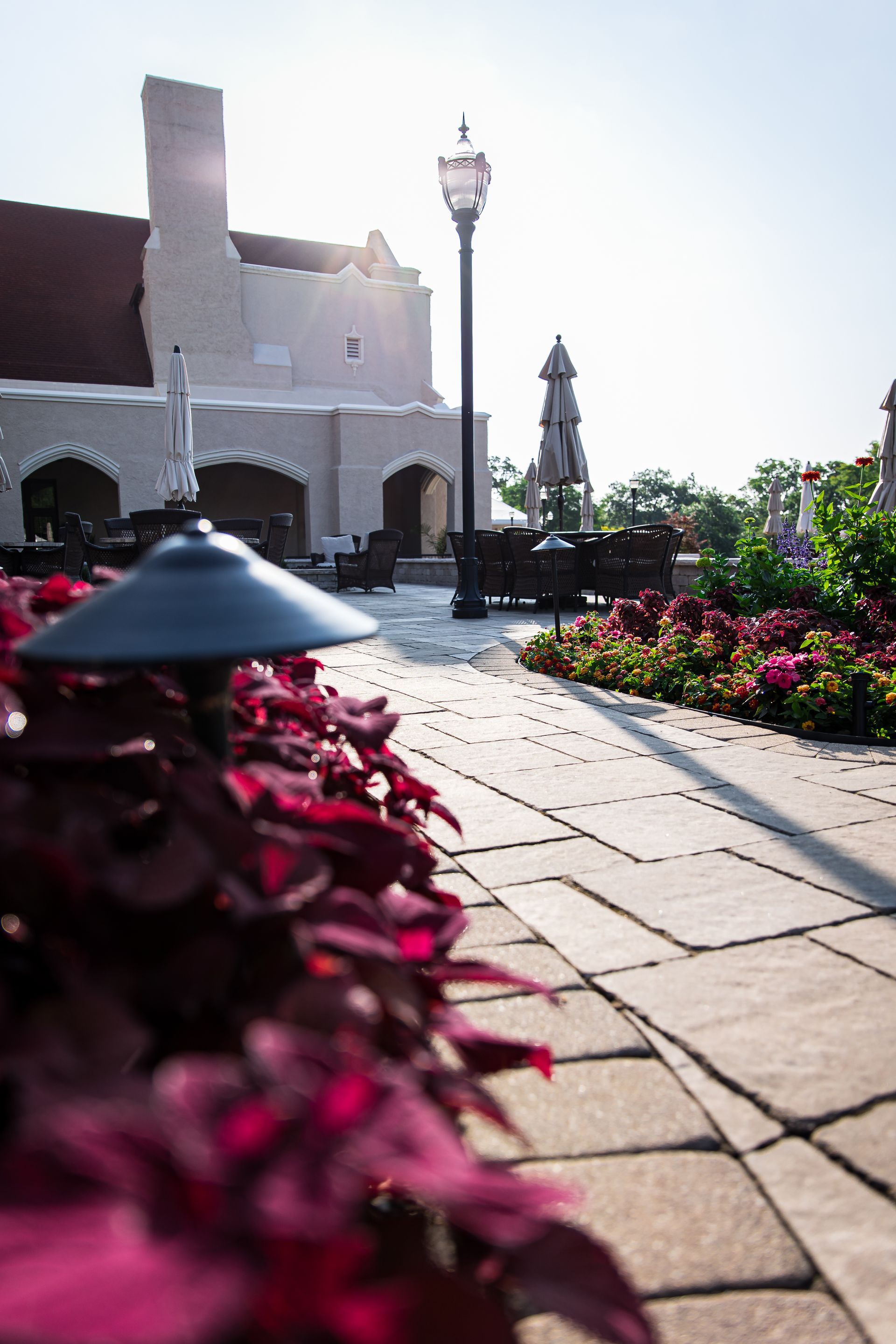 A brick walkway with flowers and a lamp post in front of a building.
