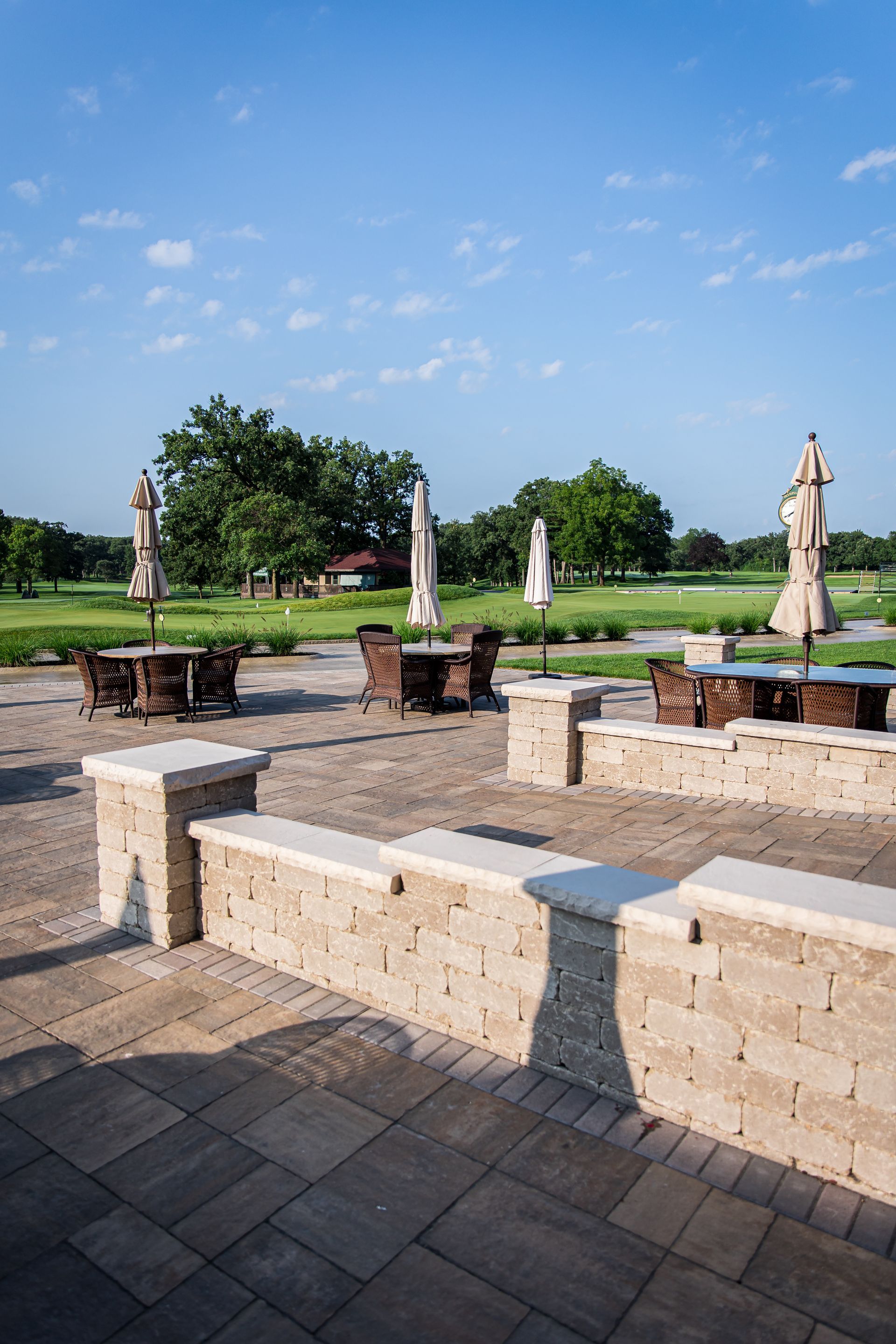 A patio with tables and chairs and umbrellas on a sunny day.