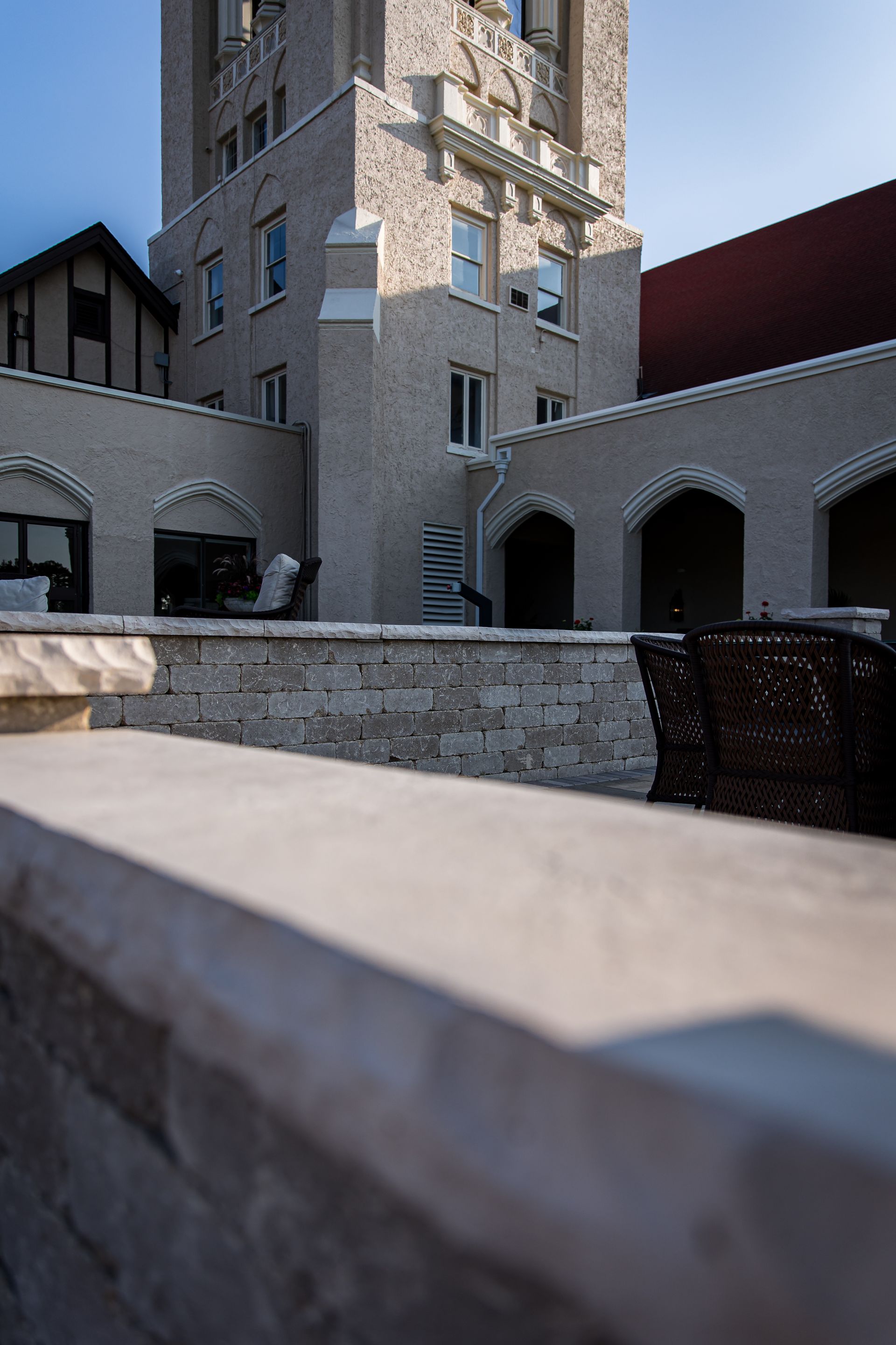 A large brick building with a clock tower is behind a stone wall.