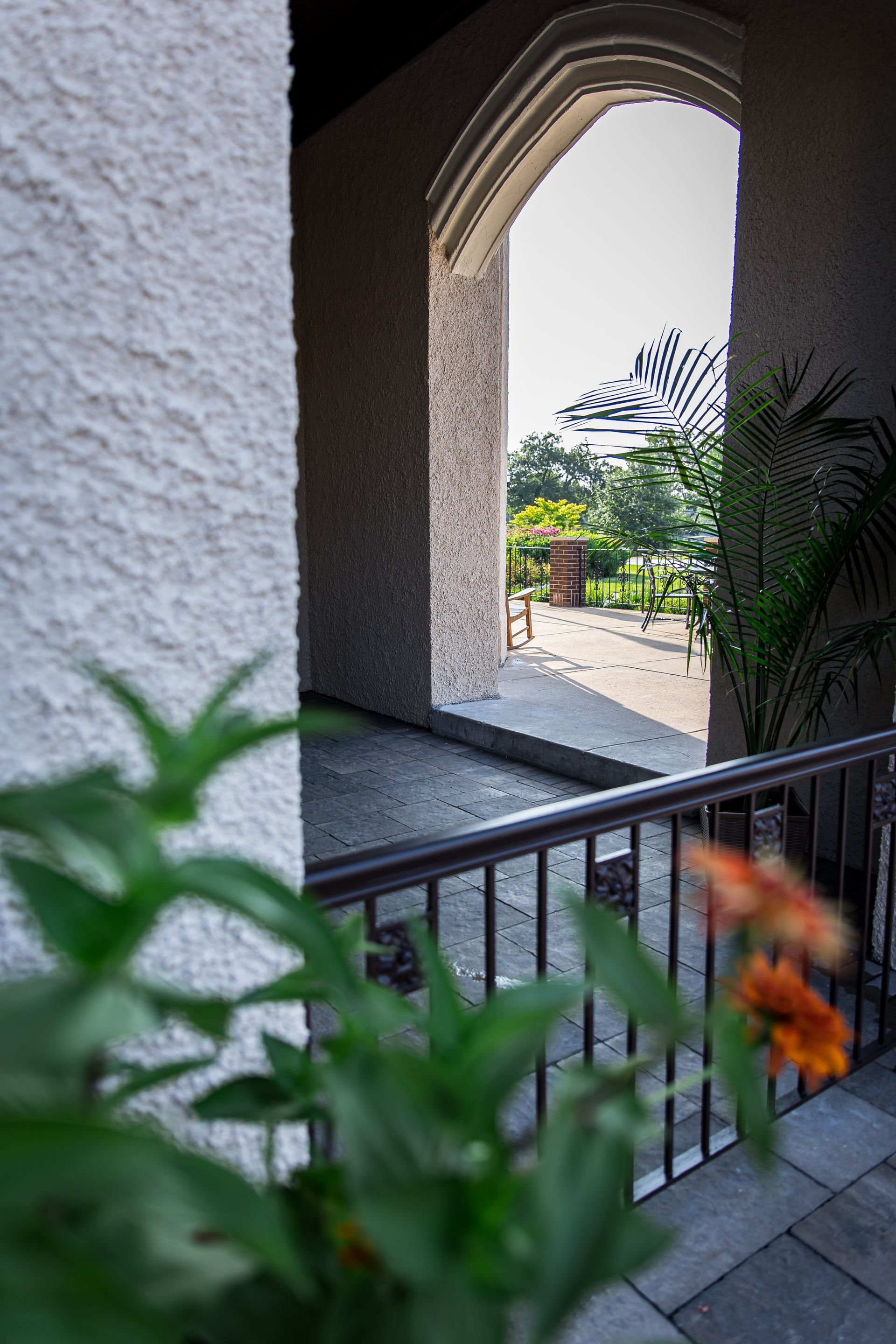 A balcony with a view of a garden through an archway.