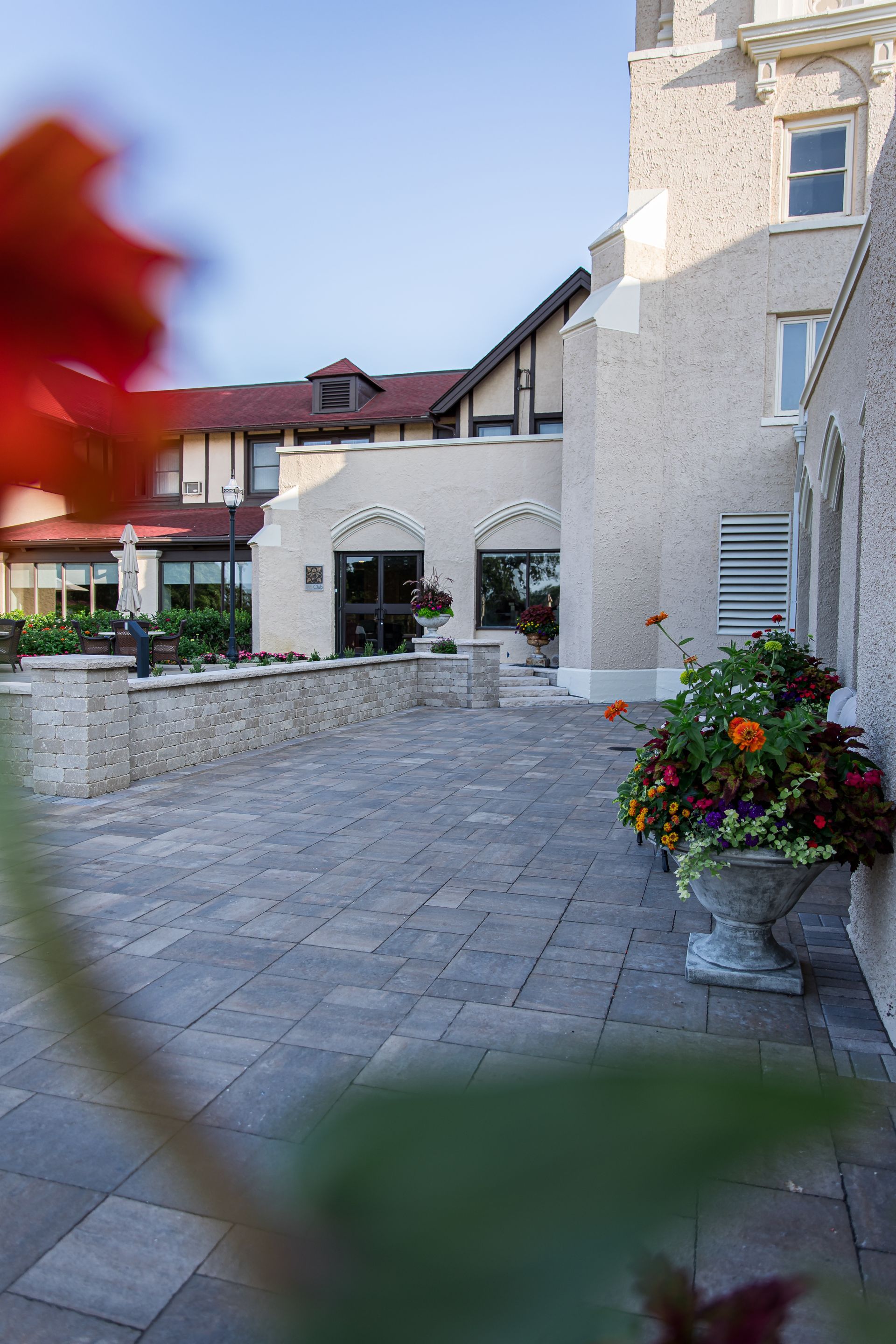 A brick walkway with a vase of flowers in front of a building.