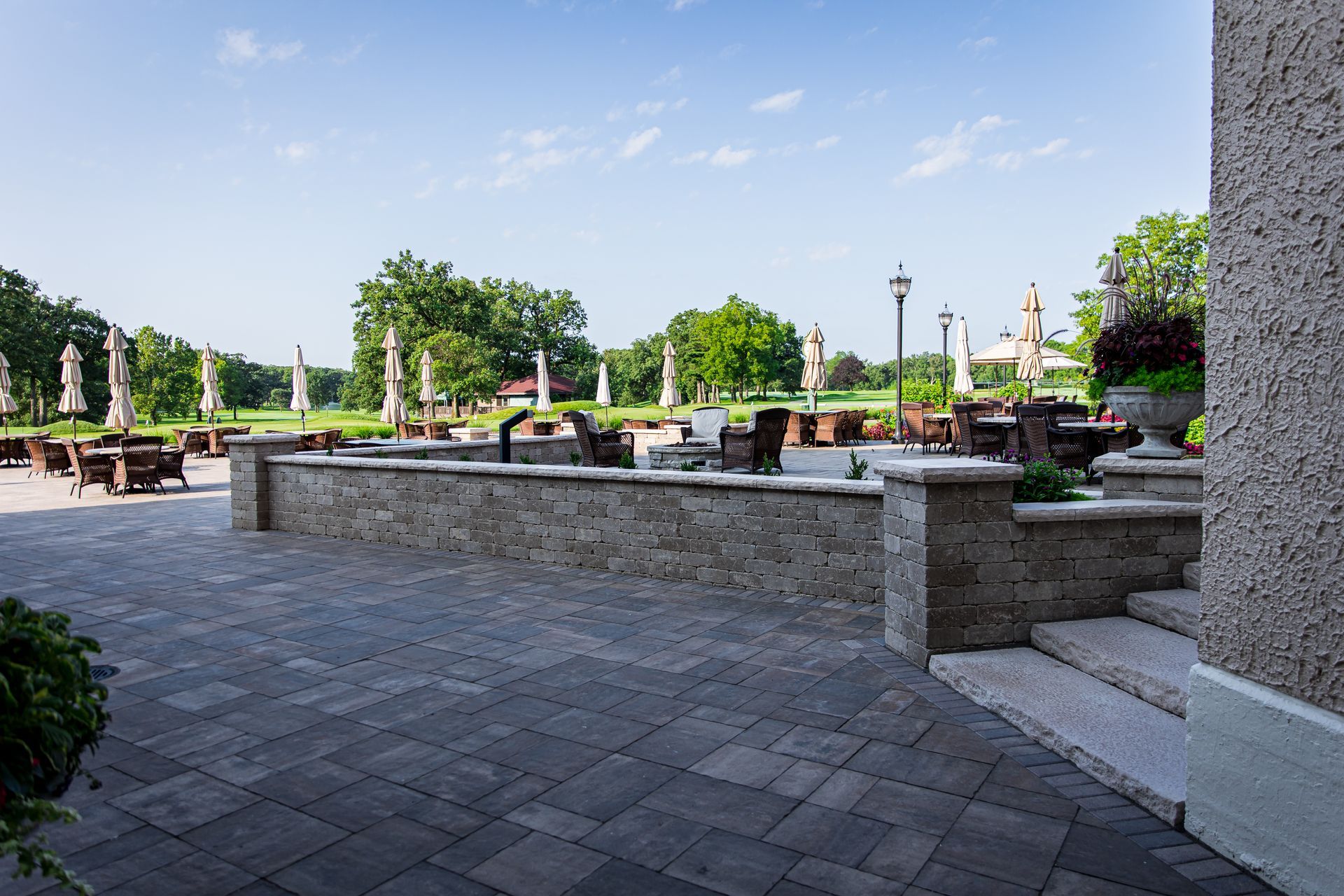 A patio with tables and chairs and umbrellas on a sunny day