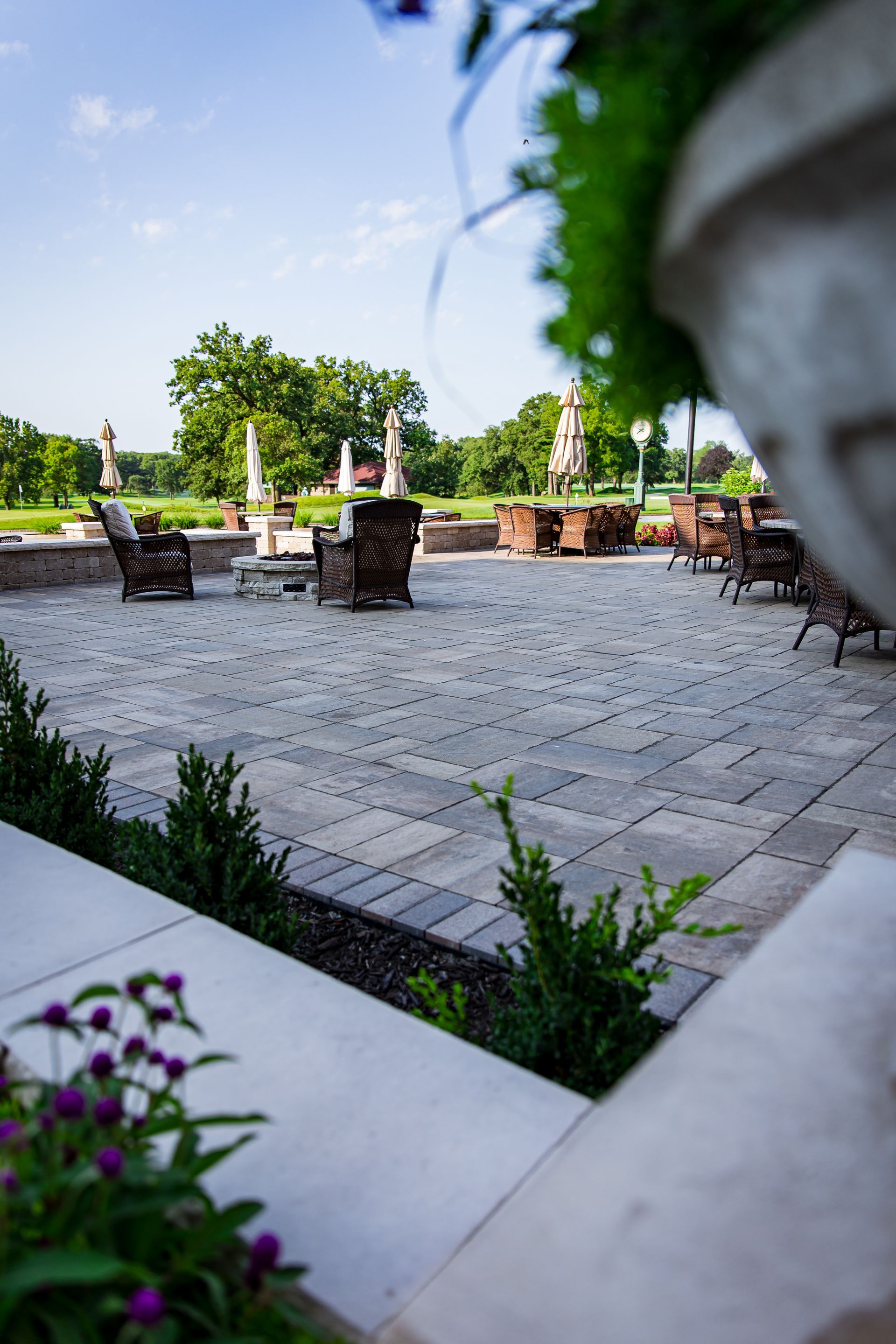 A patio with a statue in the foreground and a few chairs and tables in the background.