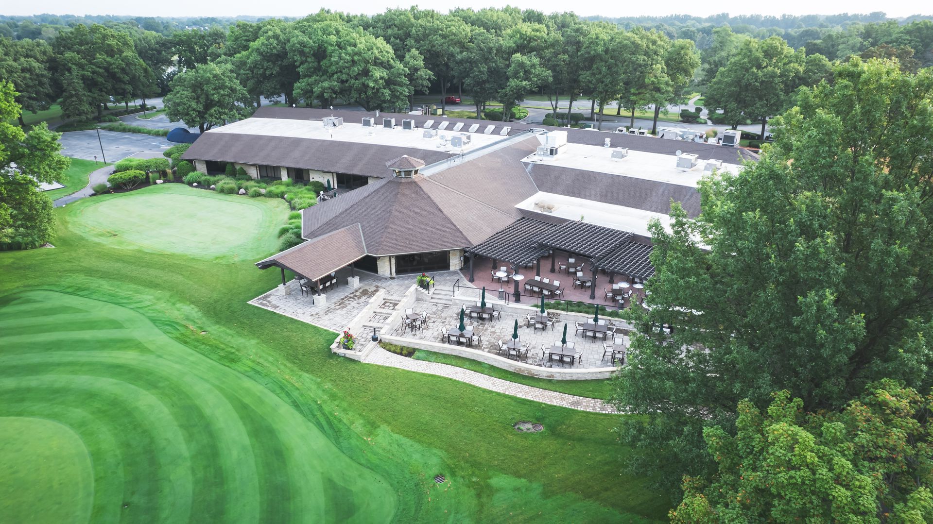 An aerial view of a golf course with a large building in the background.