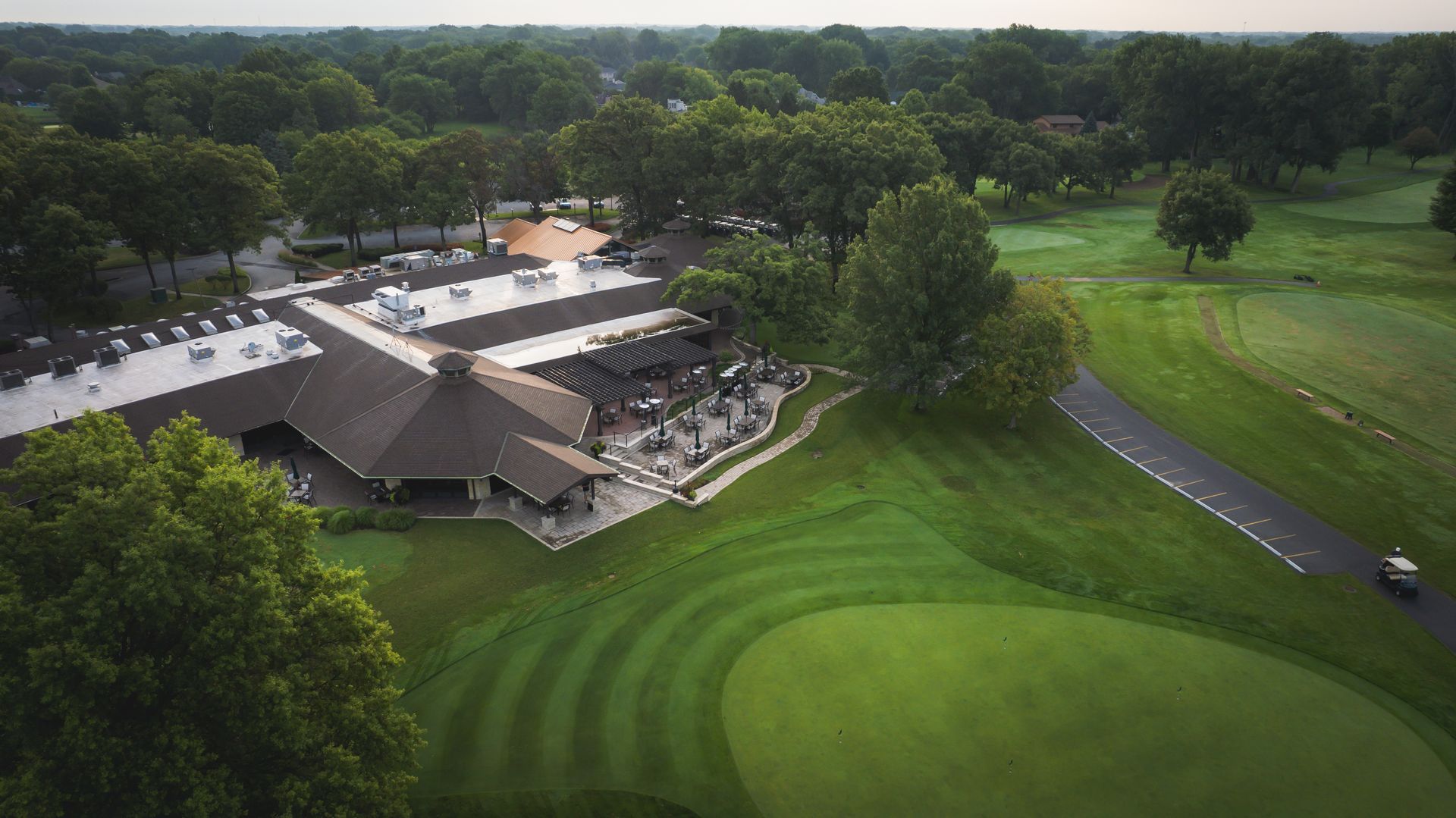 An aerial view of a golf course with a large building in the background.