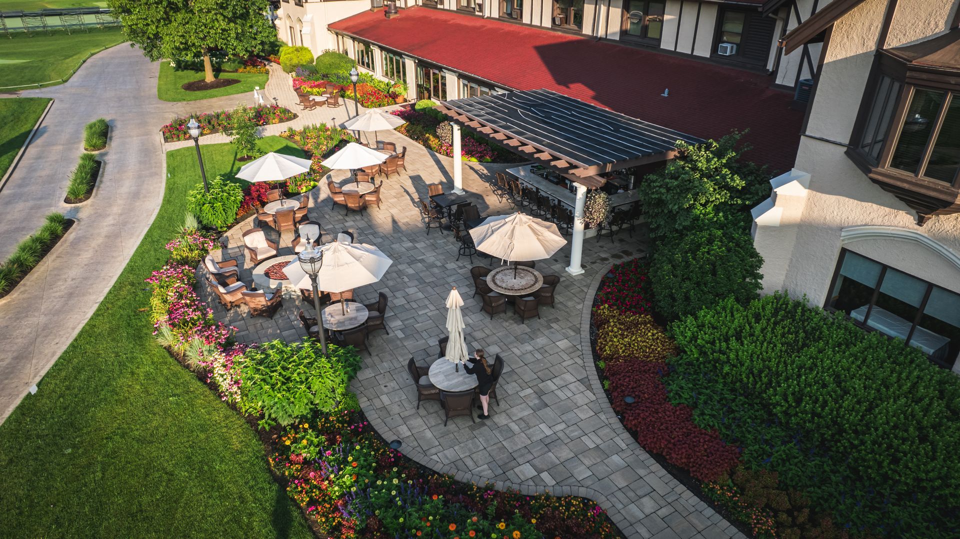 An aerial view of a patio with tables and umbrellas in front of a building.