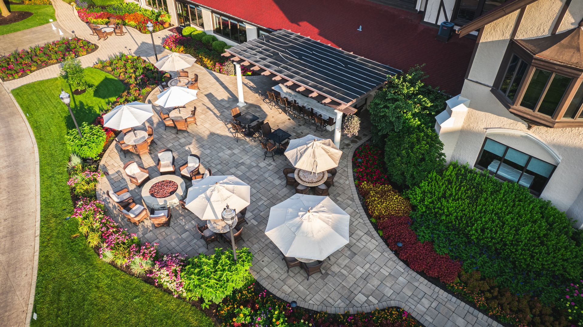 An aerial view of a patio with tables and umbrellas and a fire pit.