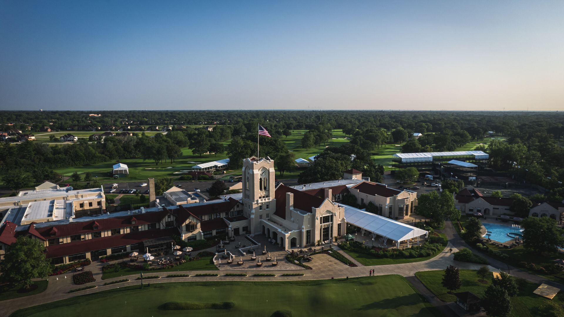 An aerial view of a large building surrounded by trees and a pool.