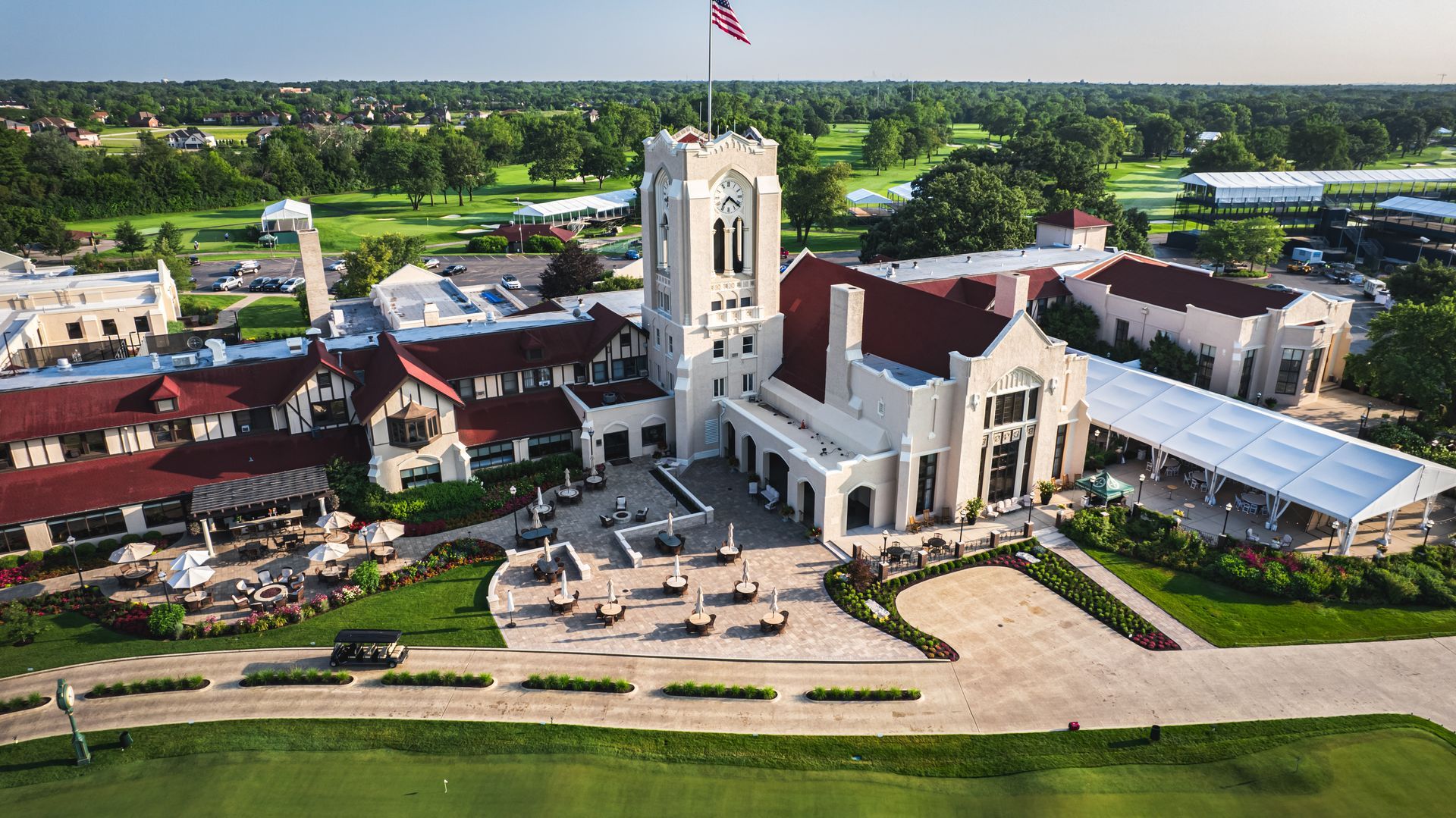 An aerial view of a large white building with a red roof surrounded by trees.