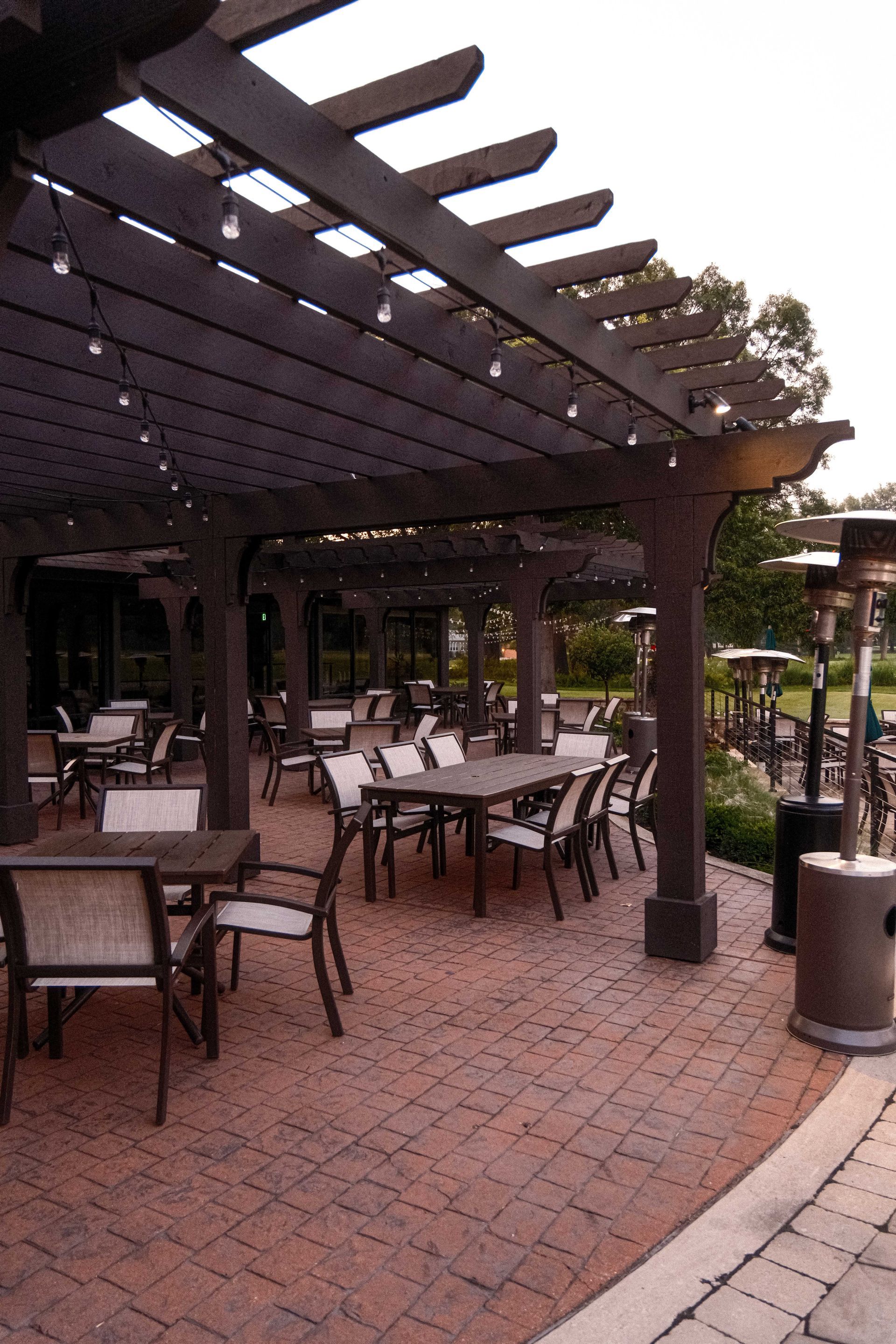 A patio with tables and chairs under a pergola