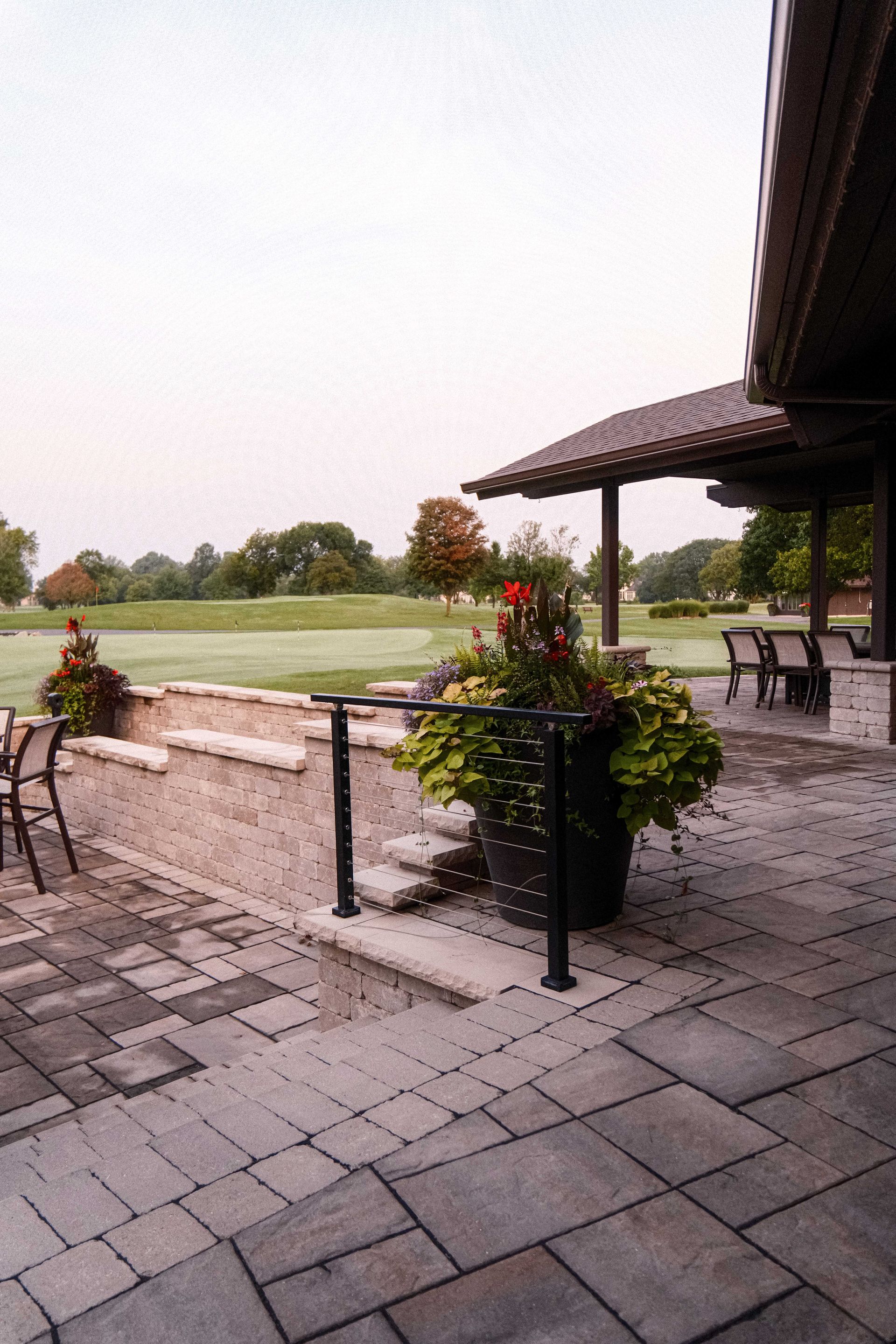 A patio with a potted plant on it and a view of a golf course.