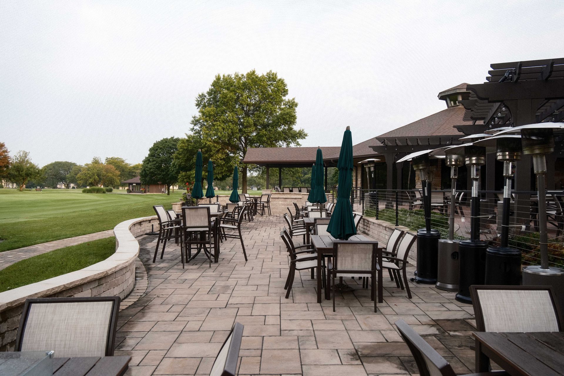 A patio with tables and chairs and umbrellas in a park.