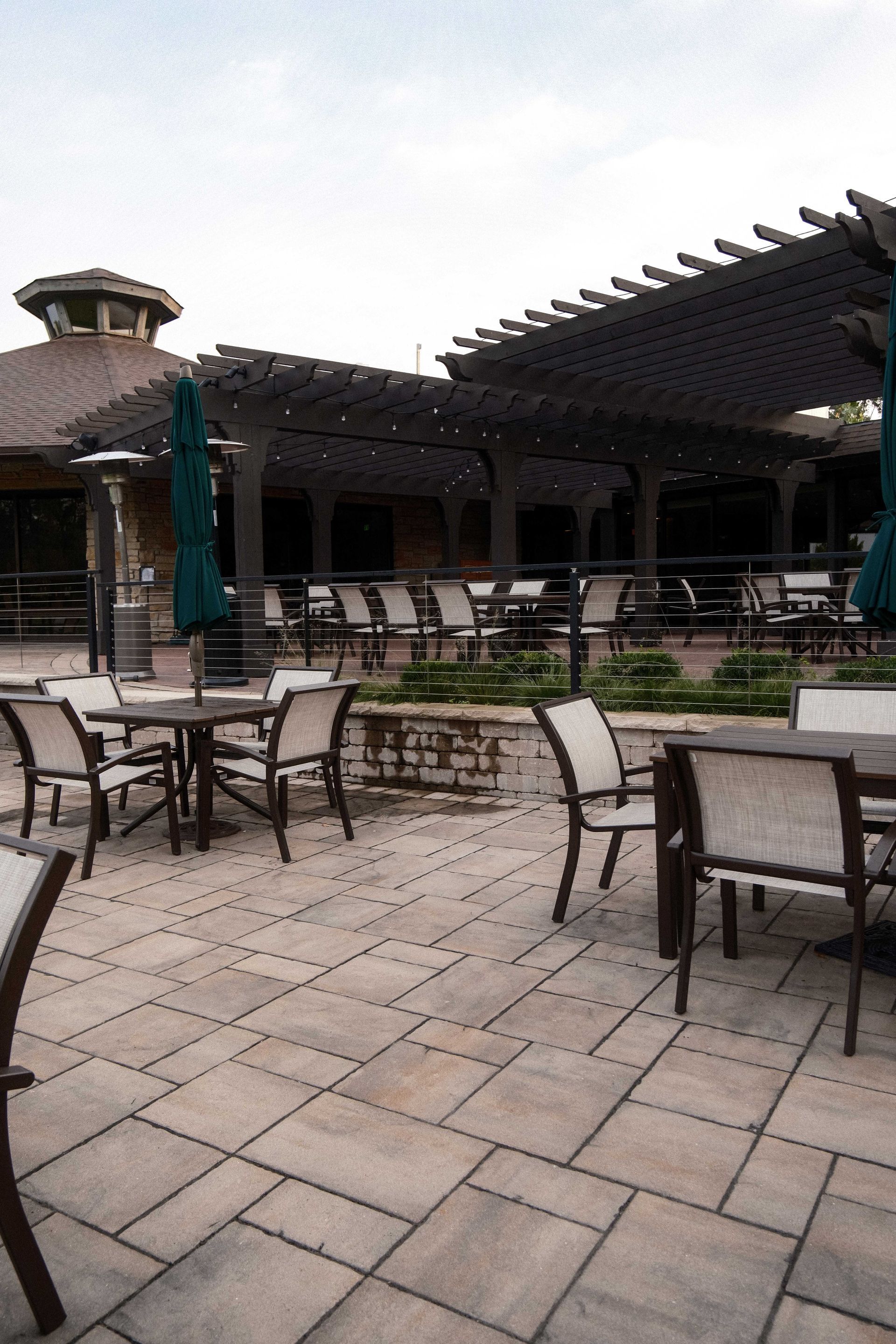 A patio with tables and chairs and umbrellas in front of a building.