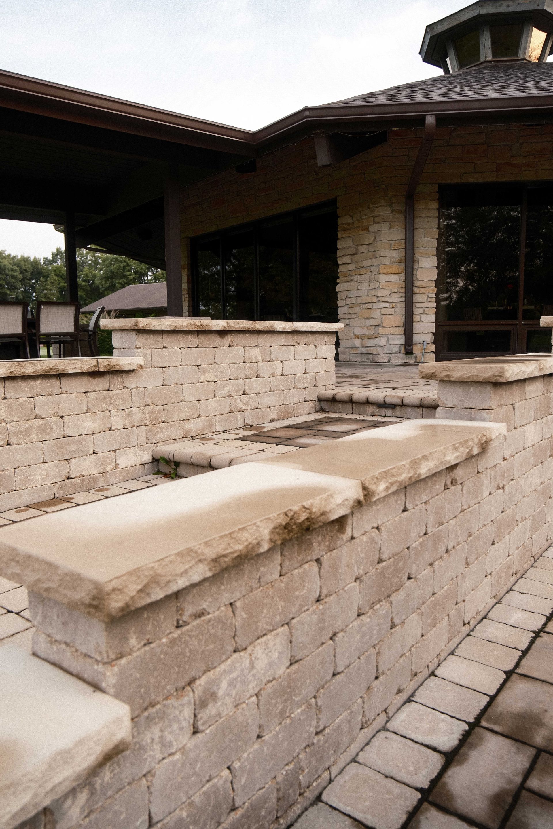 A brick wall with a bench in front of a house.