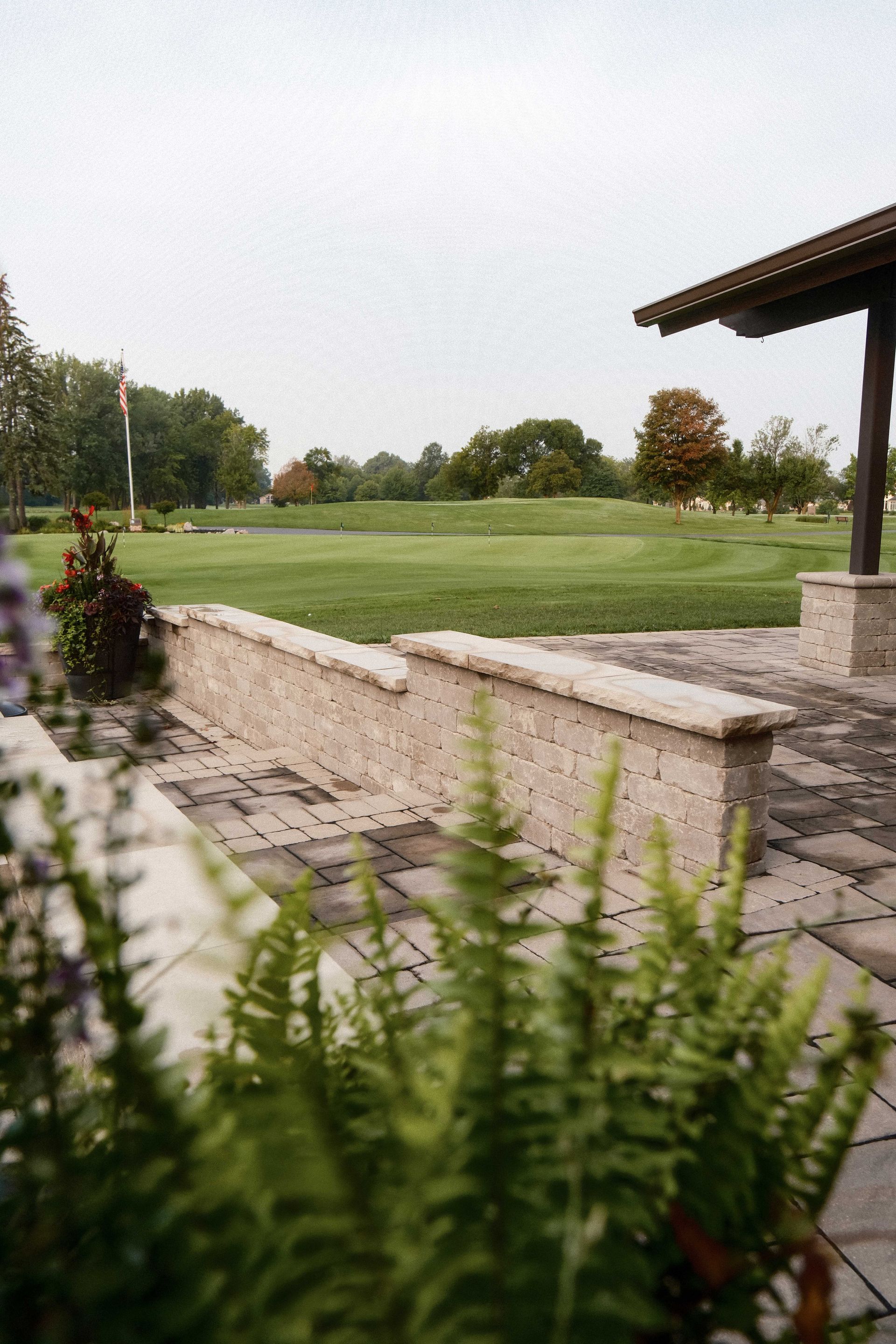 A view of a golf course from a patio with ferns in the foreground