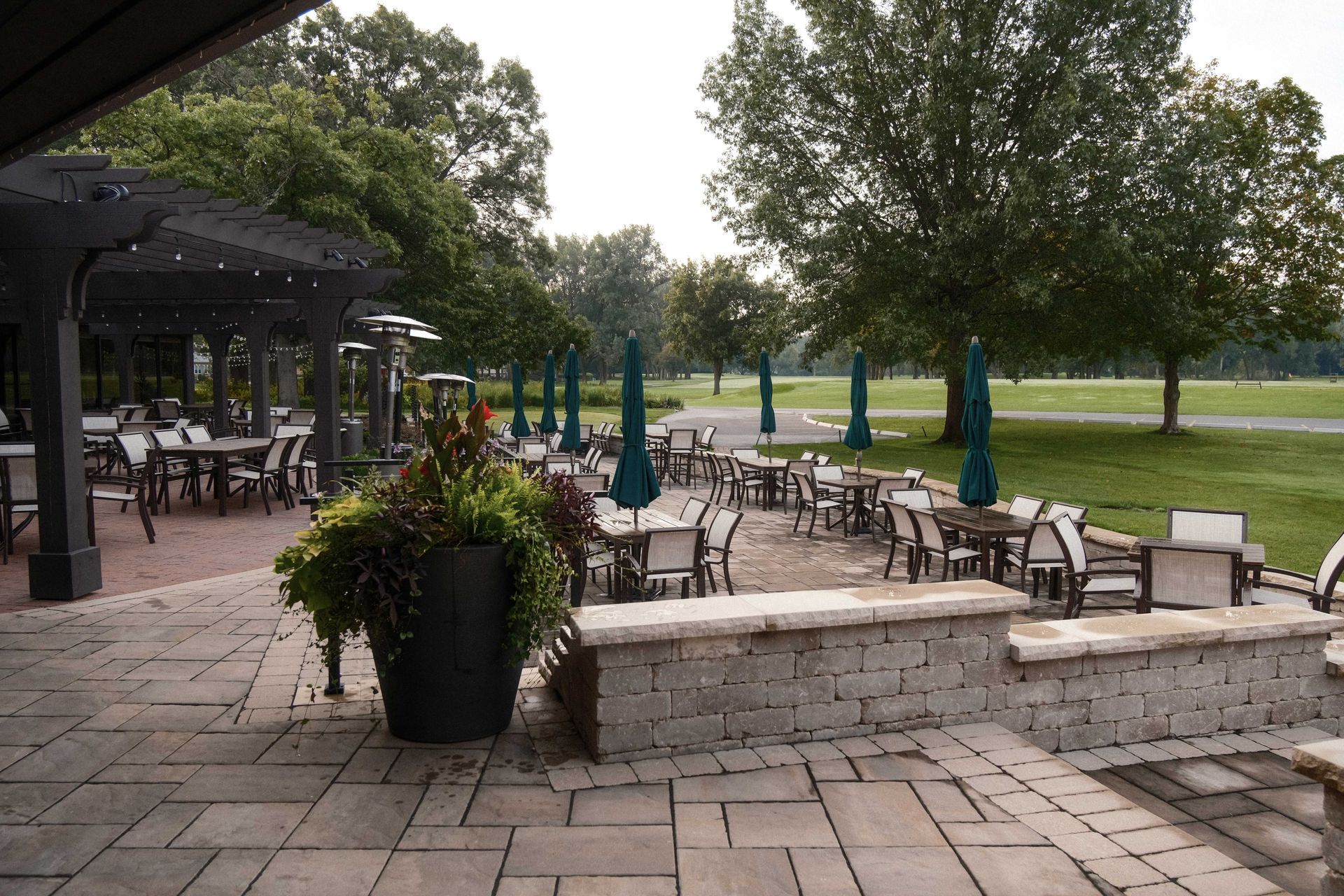 A patio with tables and chairs and umbrellas in a park