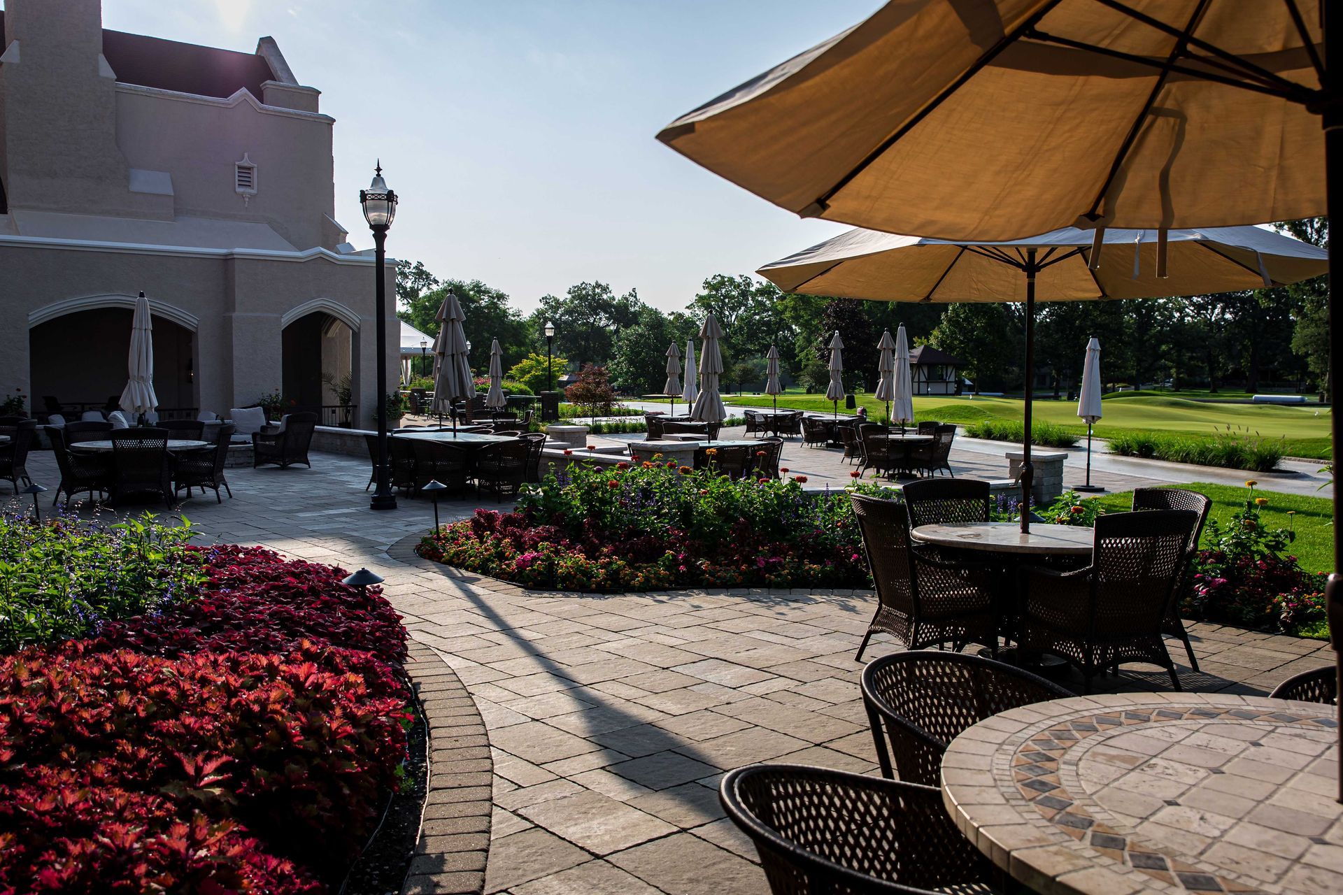 A patio with tables and chairs and umbrellas in front of a building.