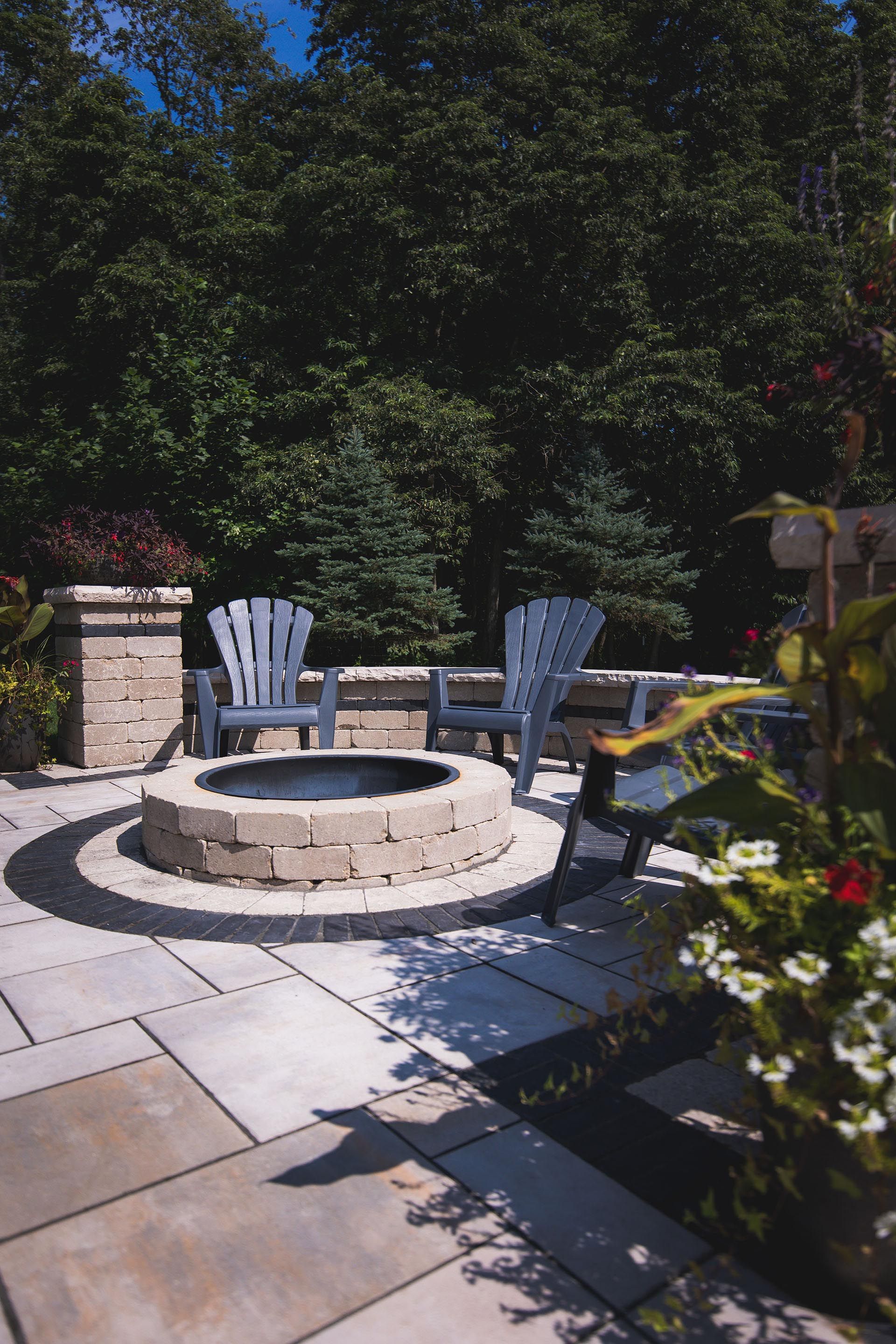 A fire pit is surrounded by chairs on a patio.