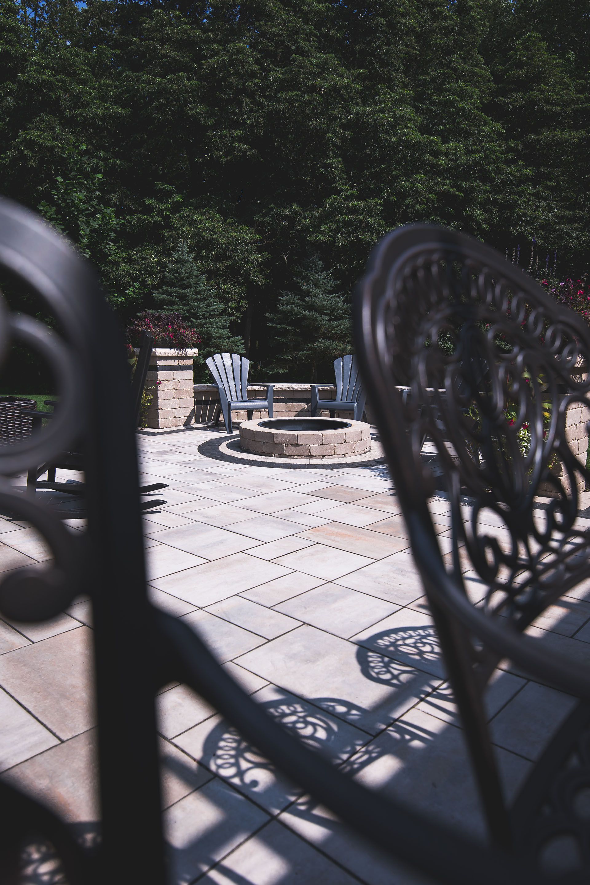 A patio with a fire pit and chairs behind a fence