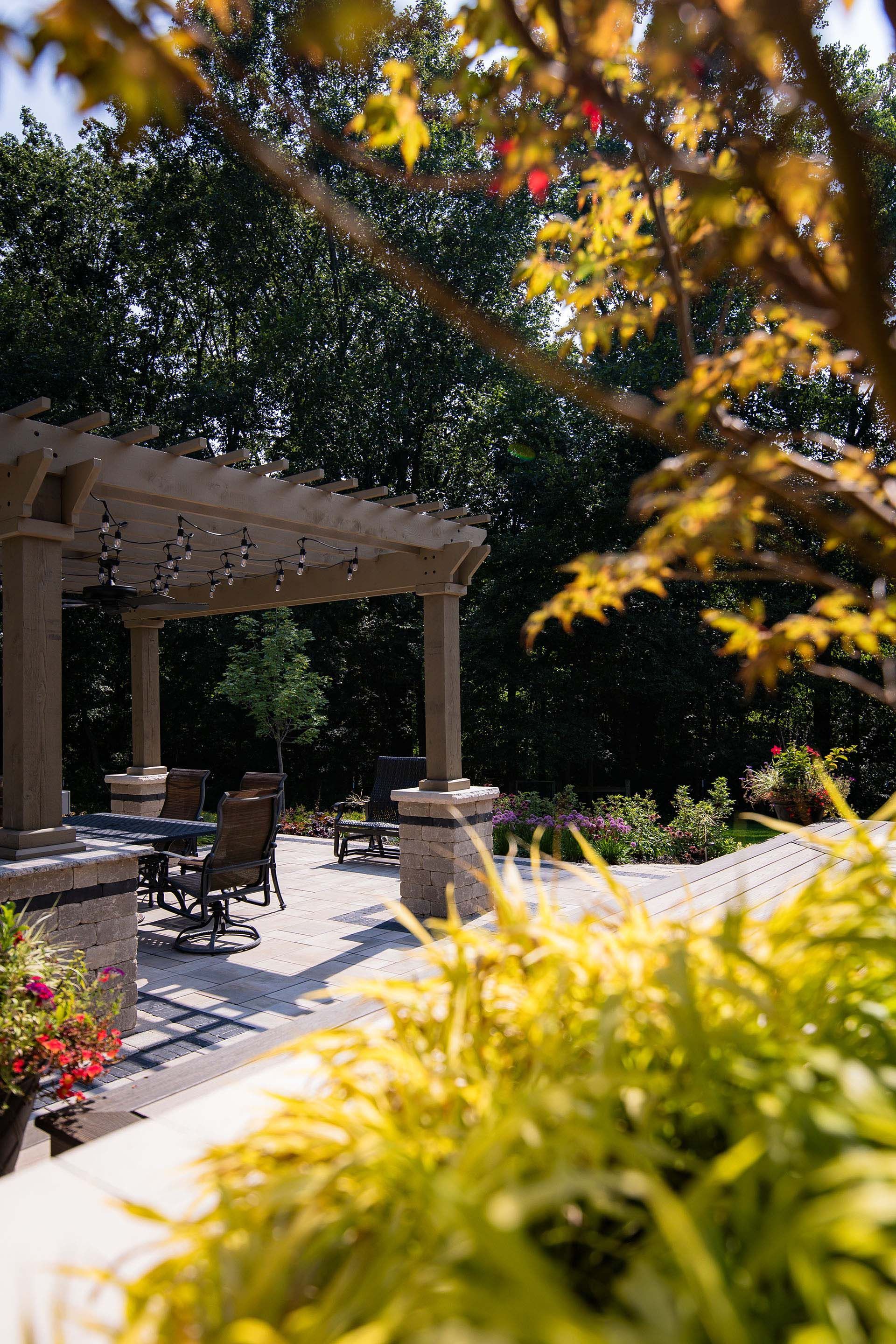 A patio with a pergola and a table and chairs in the backyard.